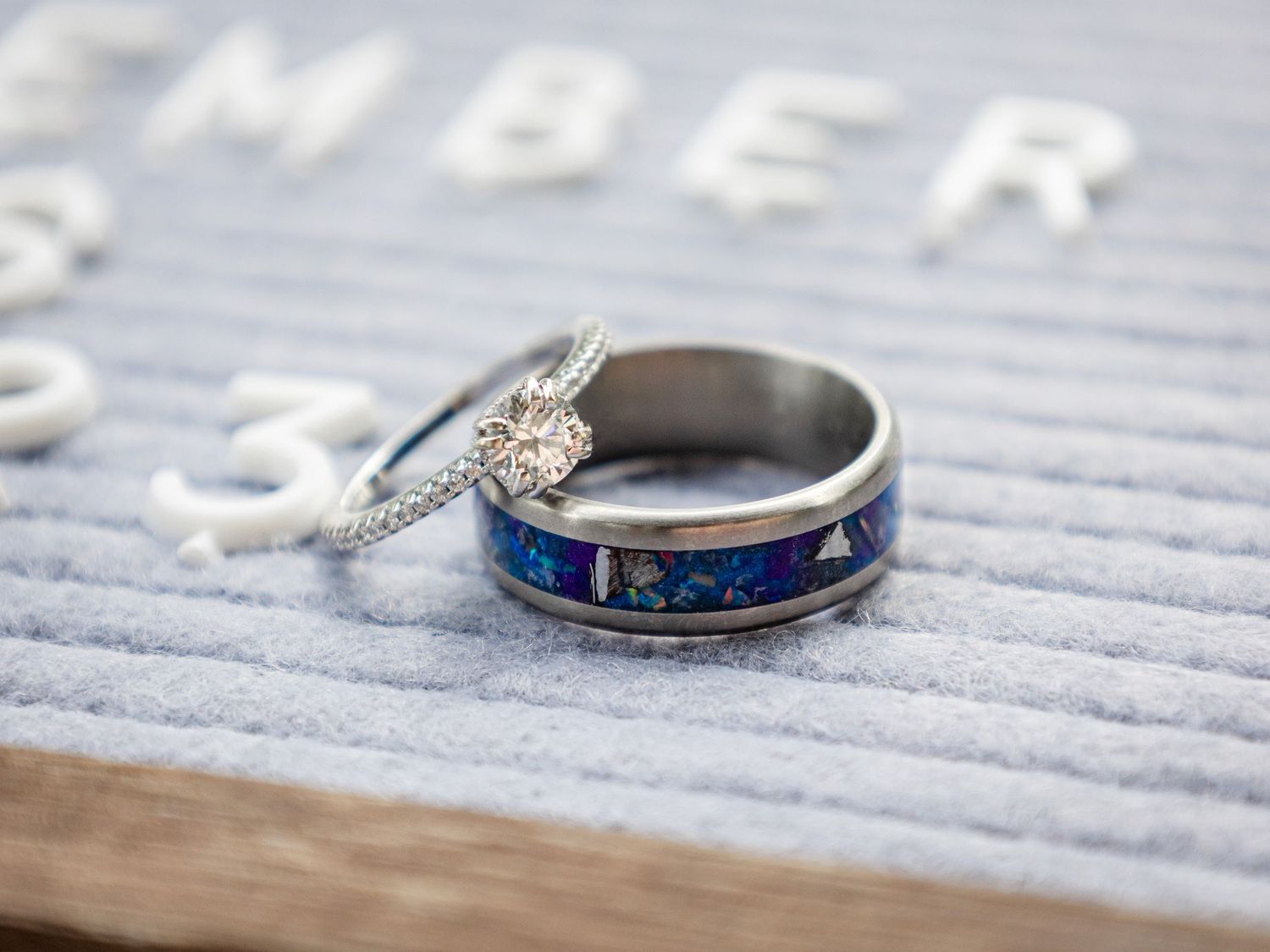 Close-up macro shots of blue and silver wedding rings with intricate details on a textured gray surface.