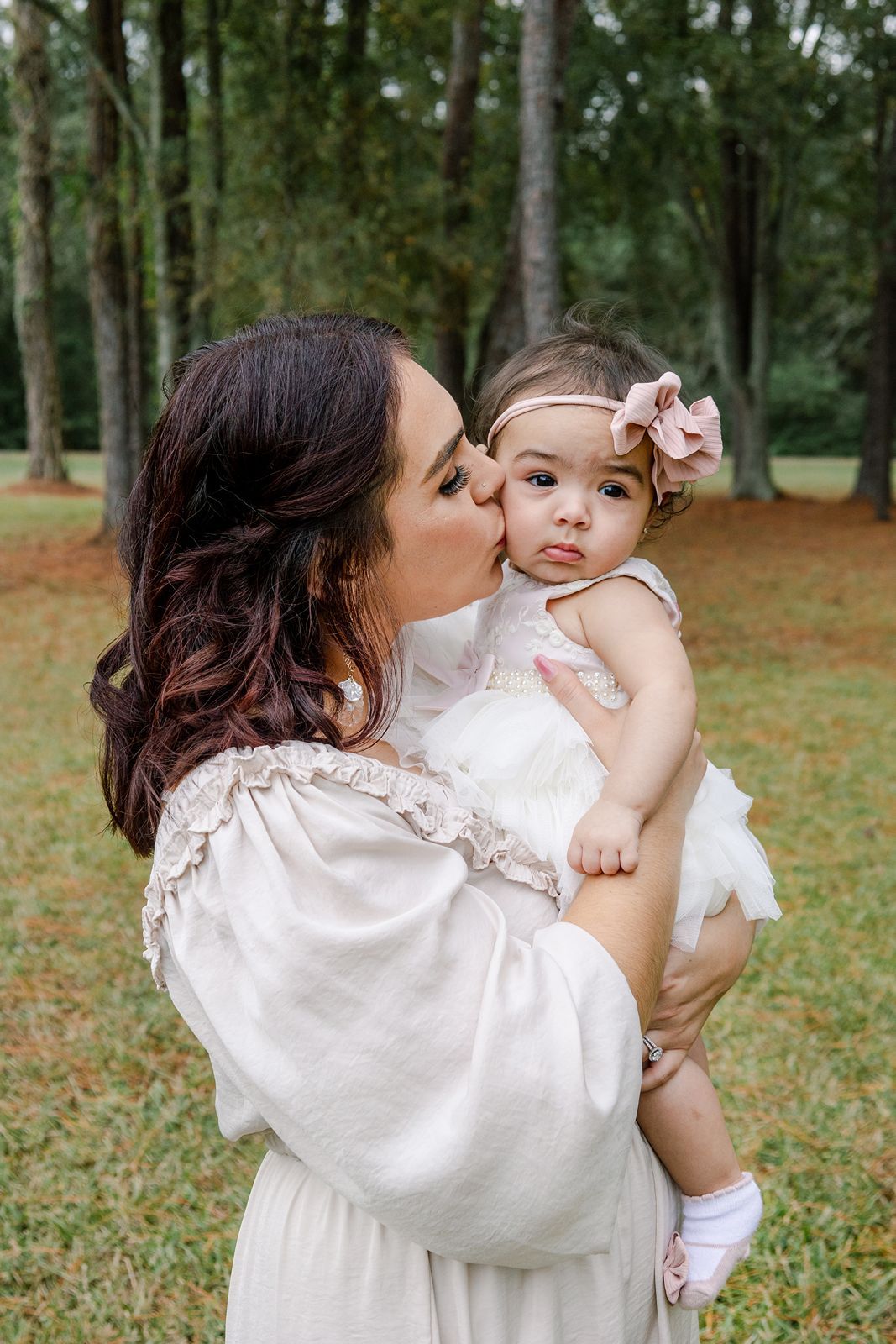 Four sequential photos showing tender moments between parent and baby in a wooded outdoor setting.