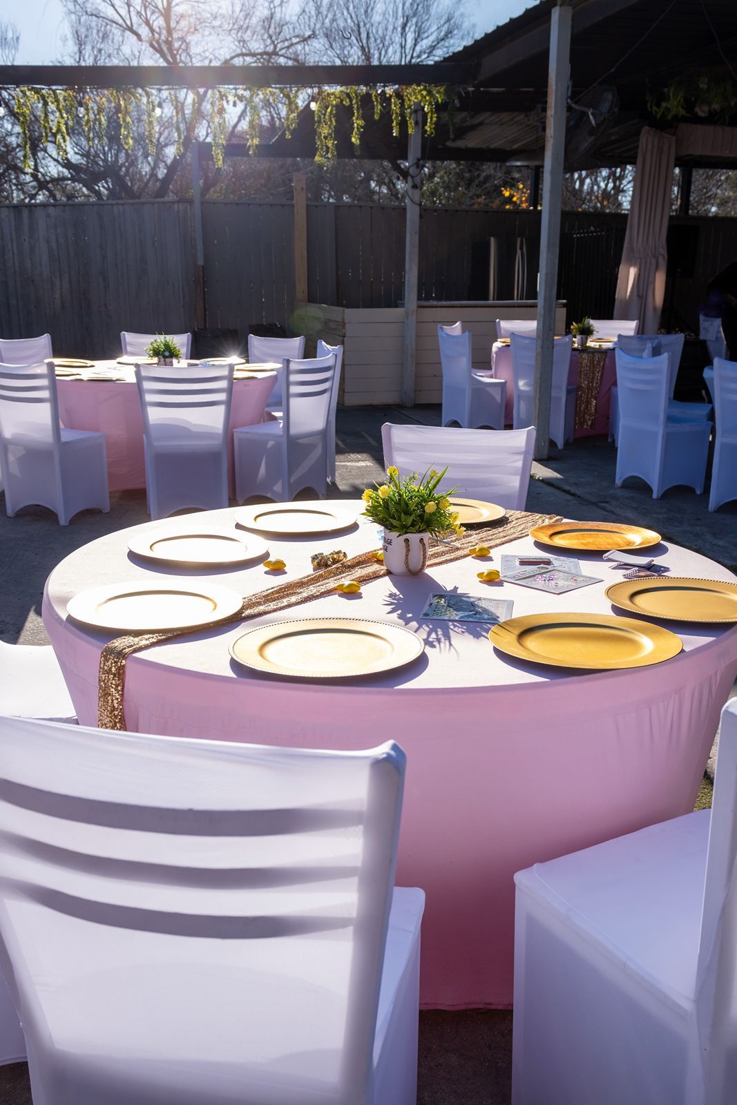 Elegant outdoor wedding reception tables with pink linens and gold charger plates.