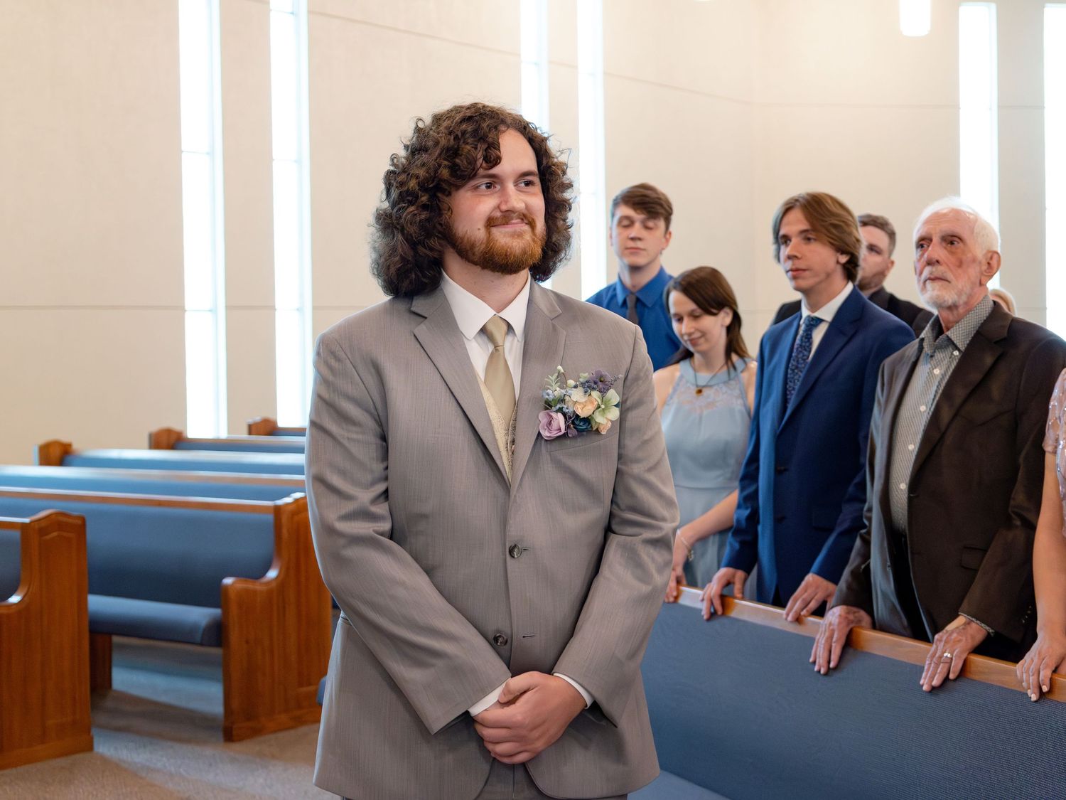 Wedding ceremony in progress at a contemporary church with wooden pews and bright lighting.