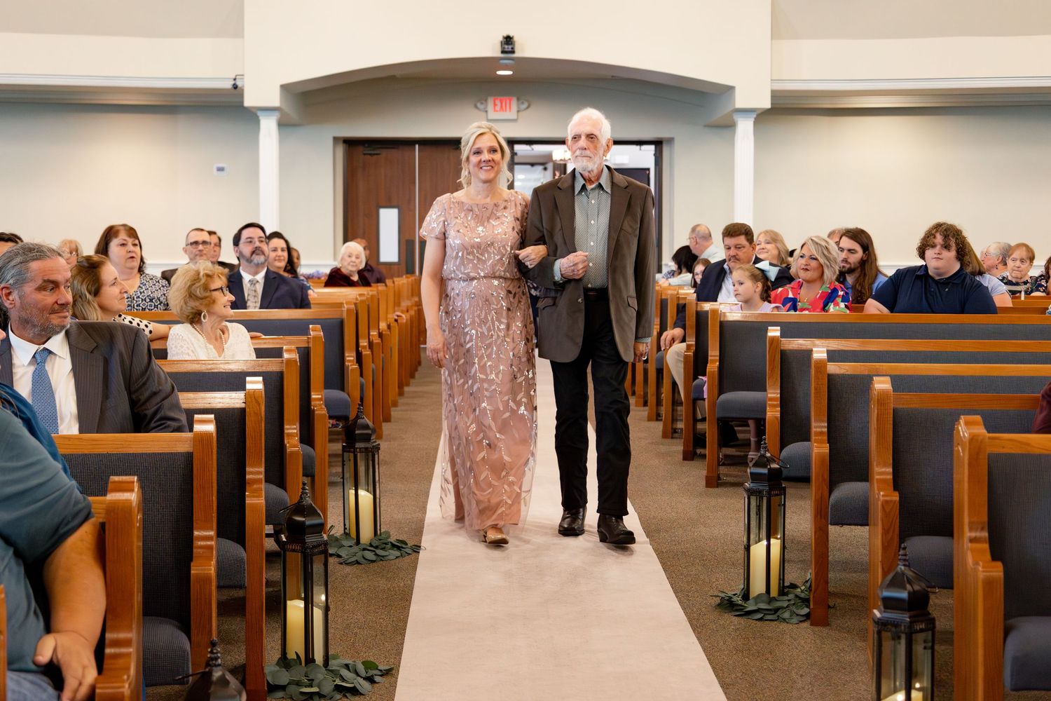 Guests fill wooden pews in a modern church sanctuary during a wedding ceremony.