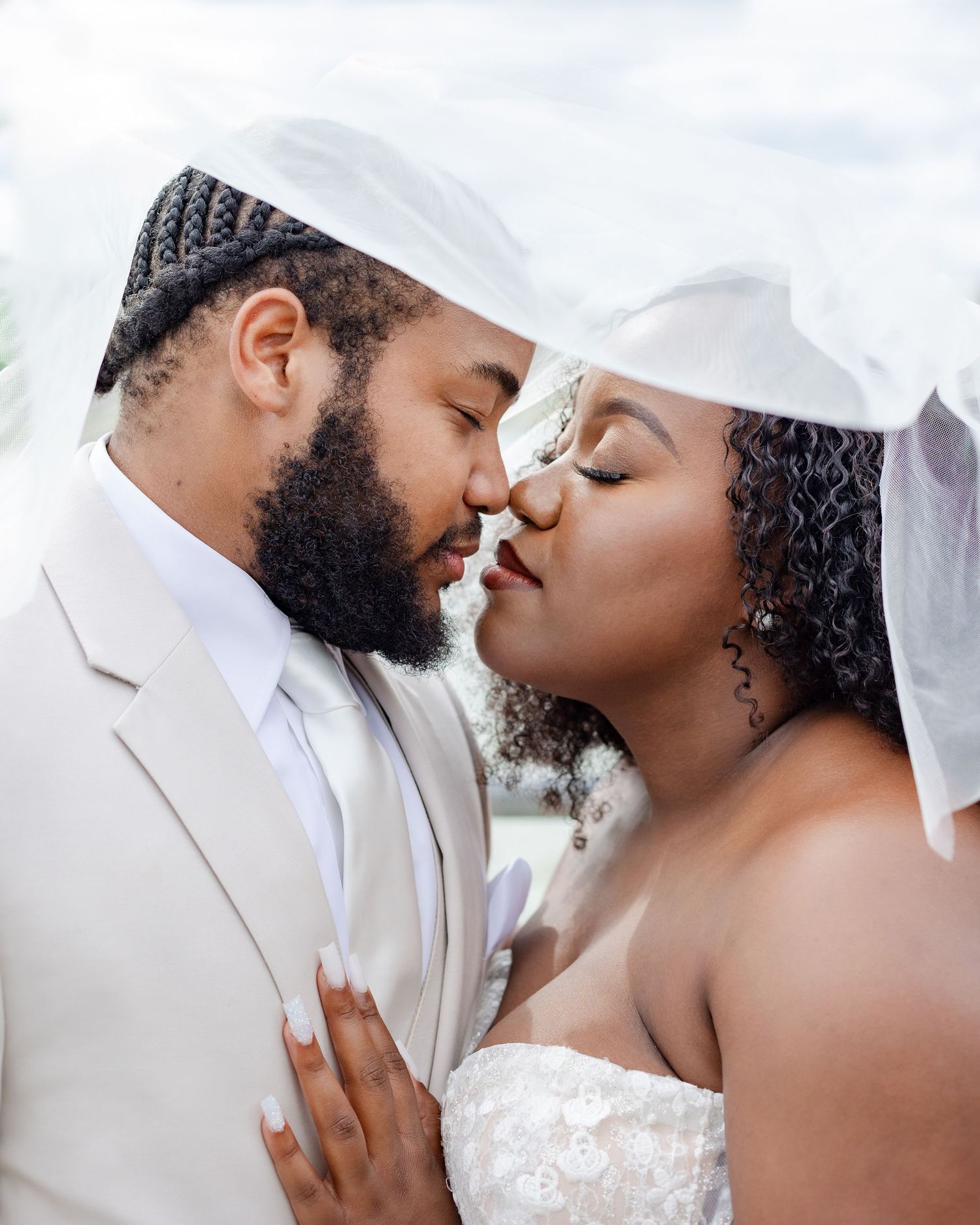 A romantic wedding moment captured as a couple in white attire share an intimate close-up embrace.