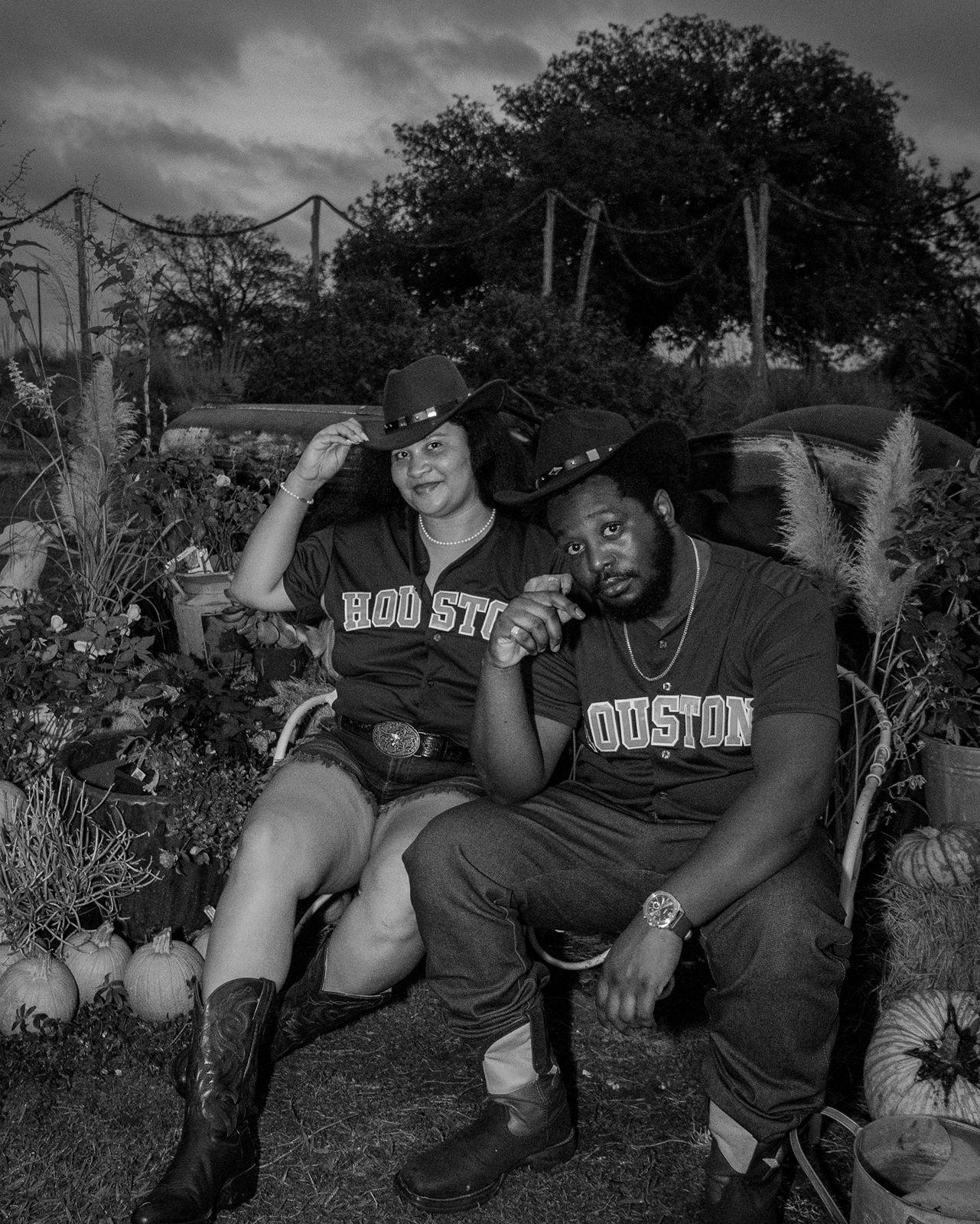 Two friends sitting and laughing together outdoors in black and white photography.