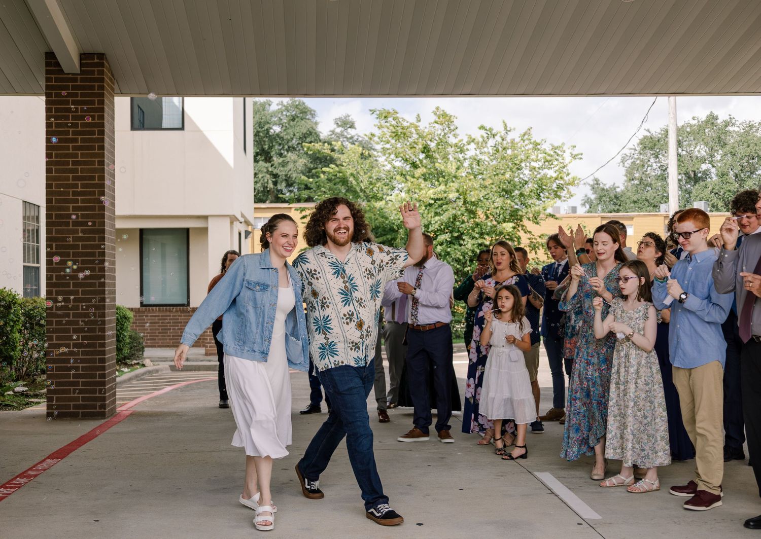 Wedding guests cheer and celebrate as a couple makes their grand exit.
