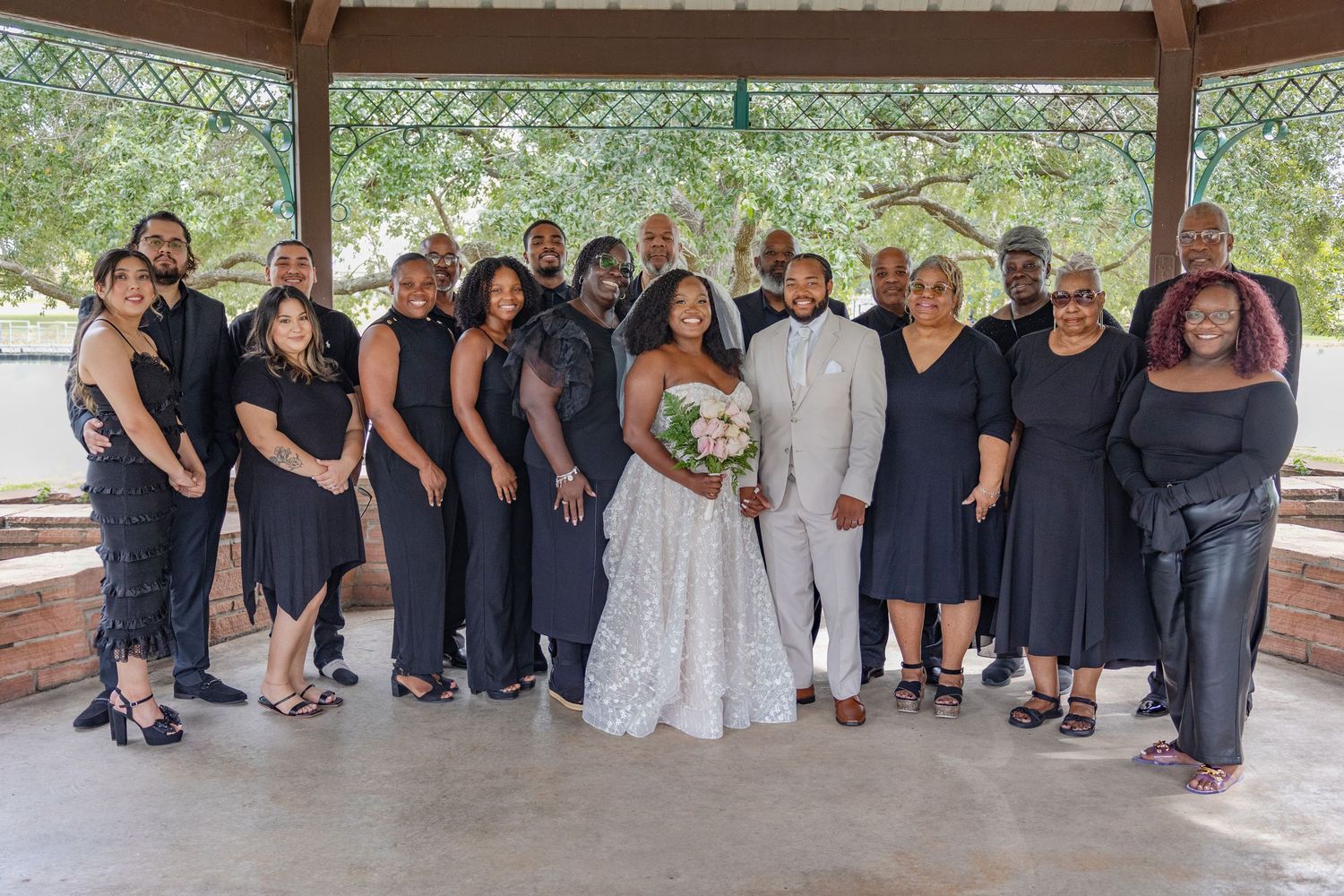 Wedding party members in navy and white attire pose beneath covered pavilion.