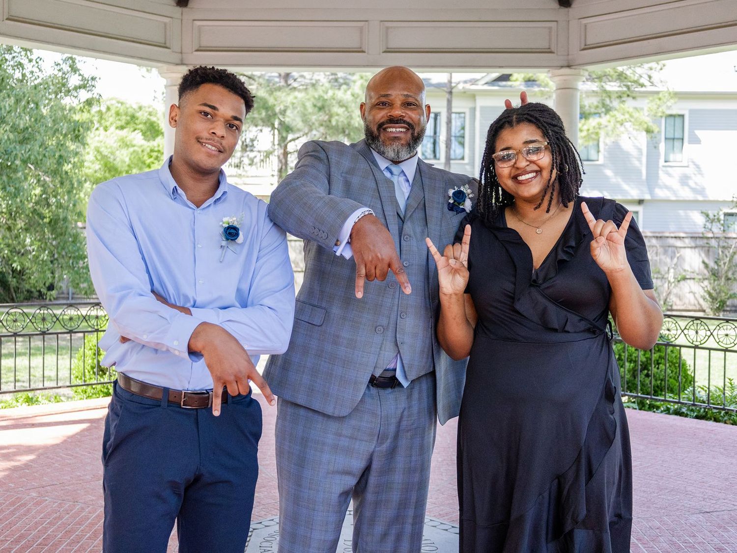 Groom in gray suit poses with son and daughter at wedding celebration outdoors.
