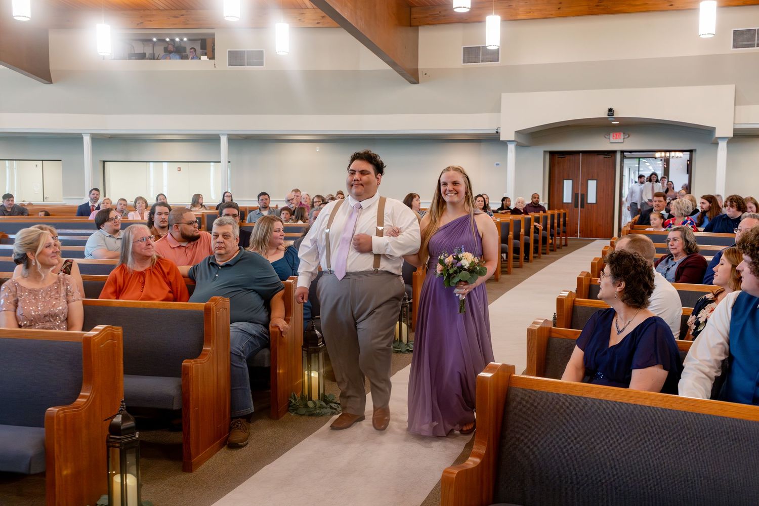 Modern church interior with wooden ceiling beams and pews filled for a wedding service.