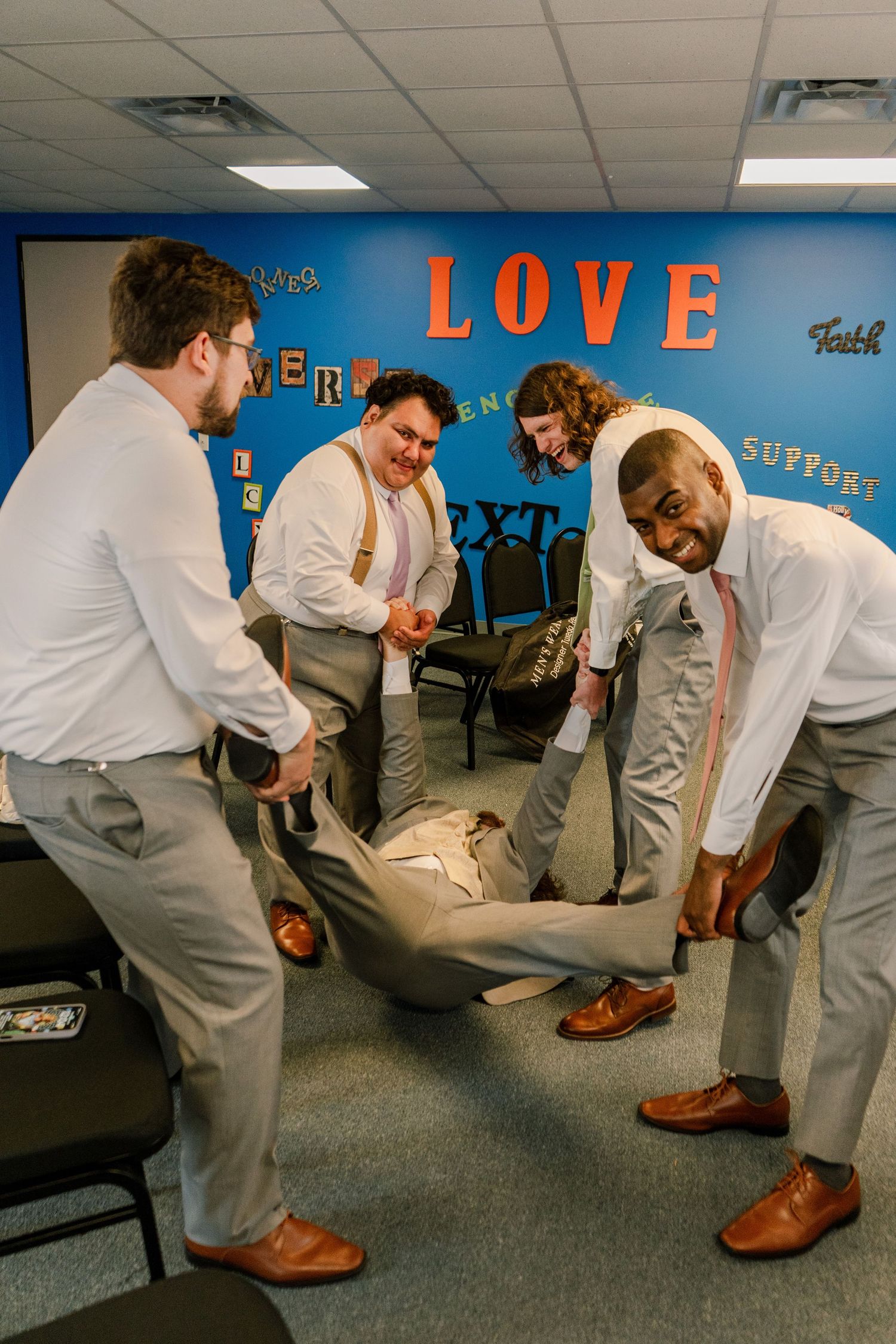 Group bending down to inspect something on the gray carpeted floor.
