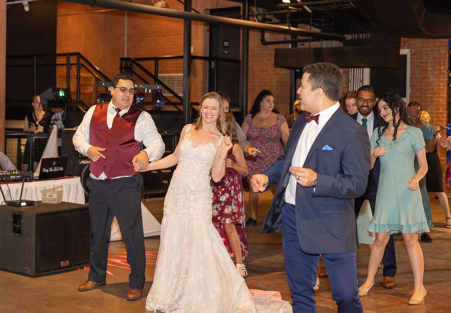 Bride and groom dancing with guests at elegant indoor wedding reception celebration.