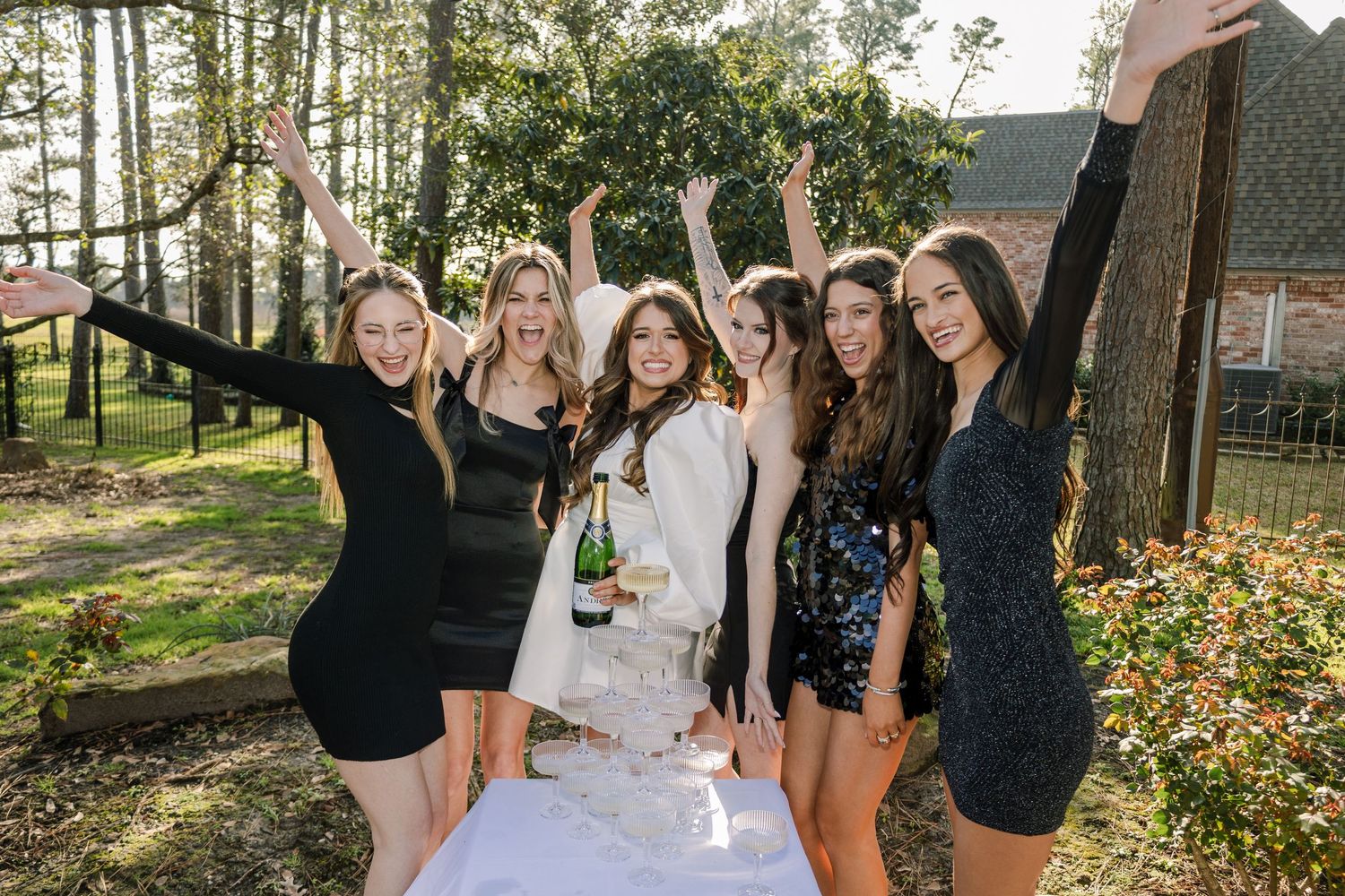 A group of people in black and white attire celebrate outdoors during a festive gathering.