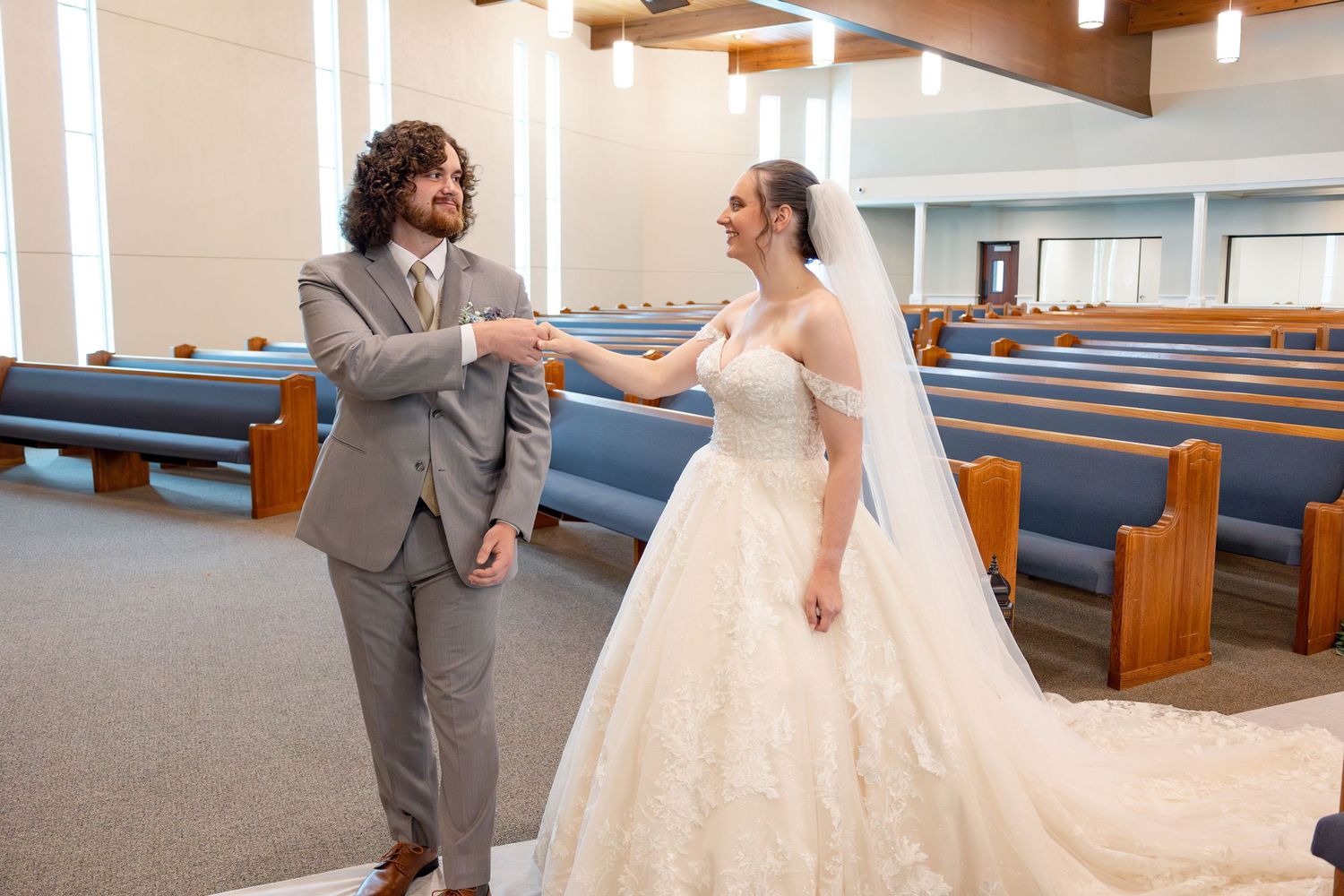 Couple shares a romantic moment in church sanctuary with wood beam ceiling and blue pews.