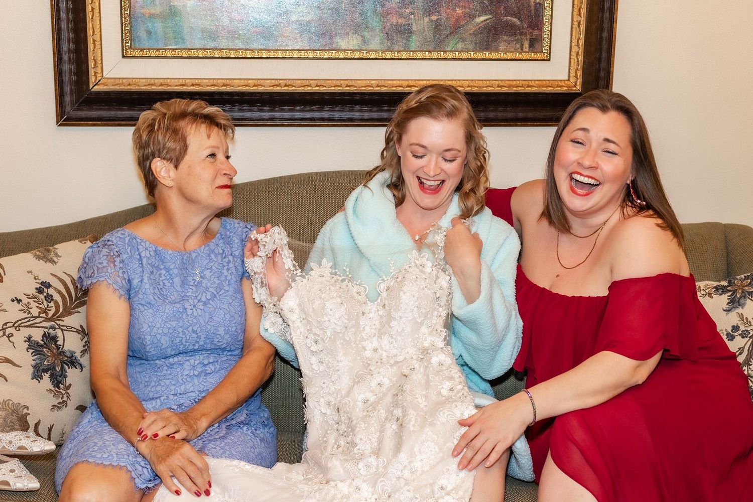 A group in formal attire shares a joyful moment together on a couch with floral artwork in the background.