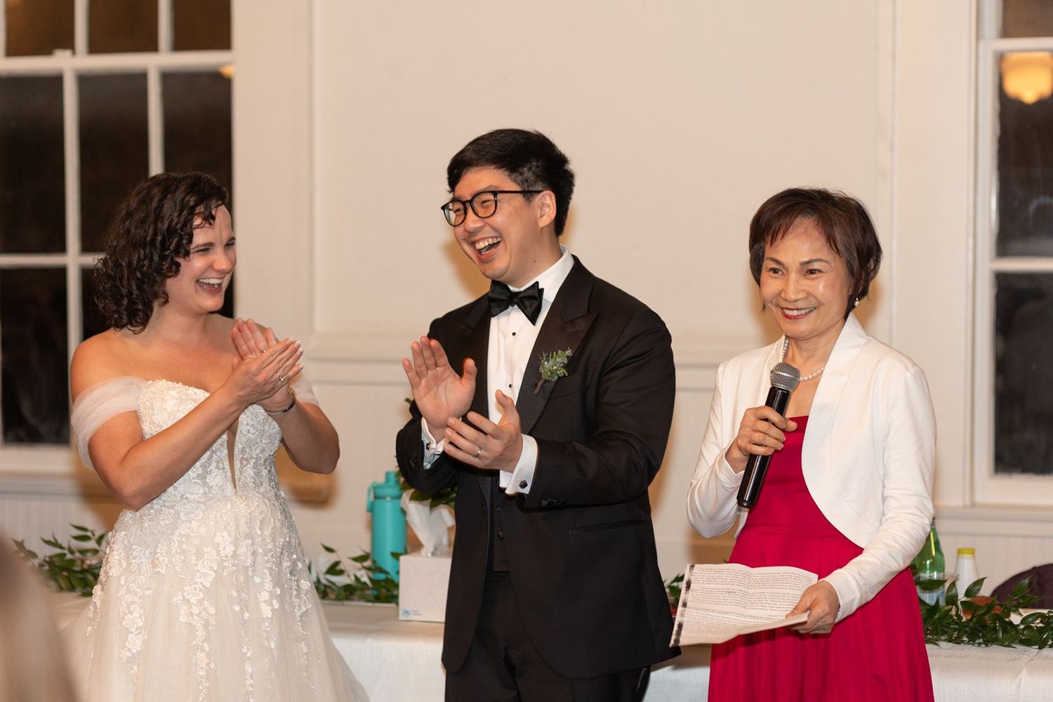 Wedding party members interact and dance during an elegant indoor celebration with formal attire.