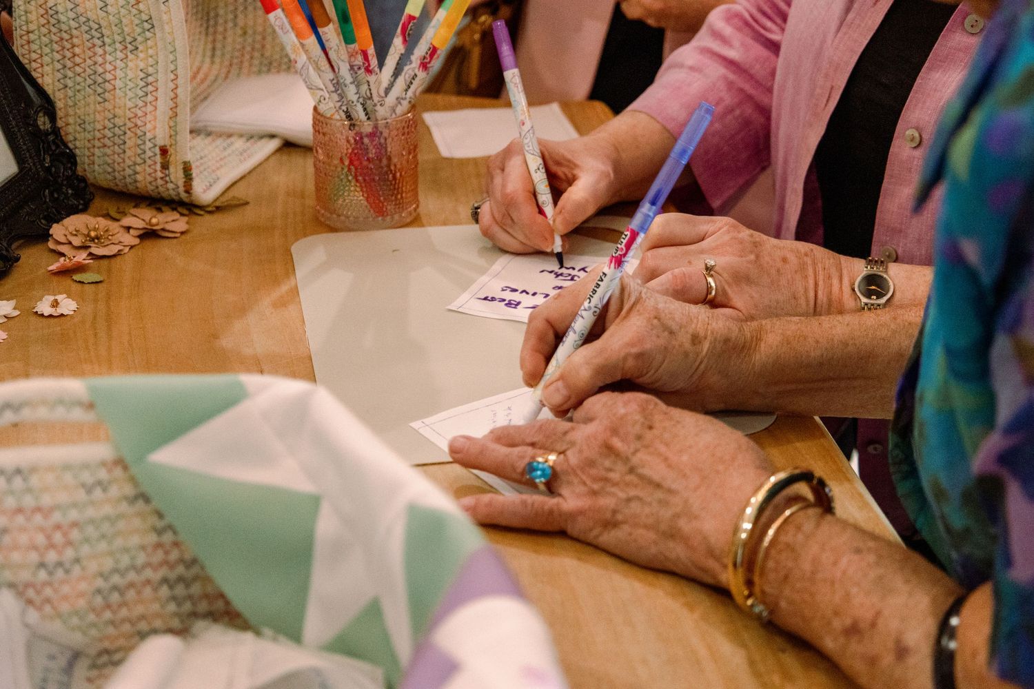 Close-up of hands signing documents on a table with papers.