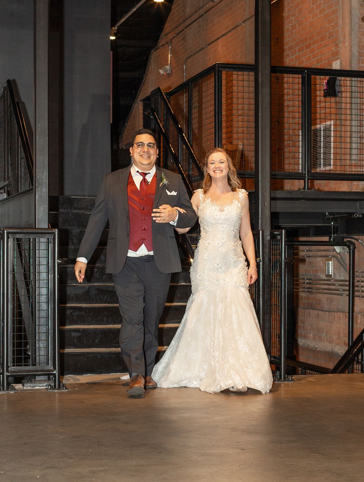 Bride and groom make grand entrance walking arm in arm through industrial wedding venue.