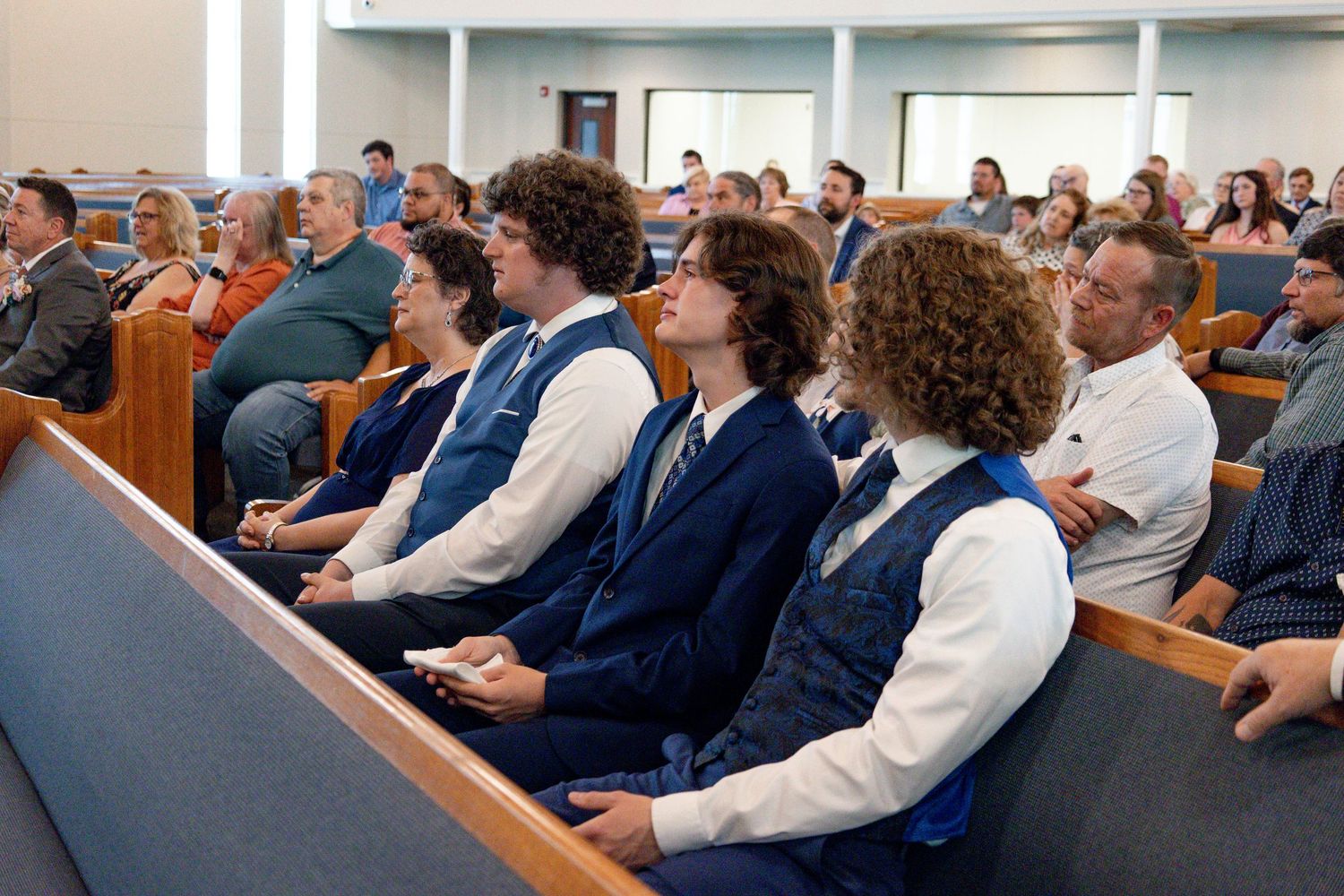 Congregation seated in church pews during wedding ceremony.