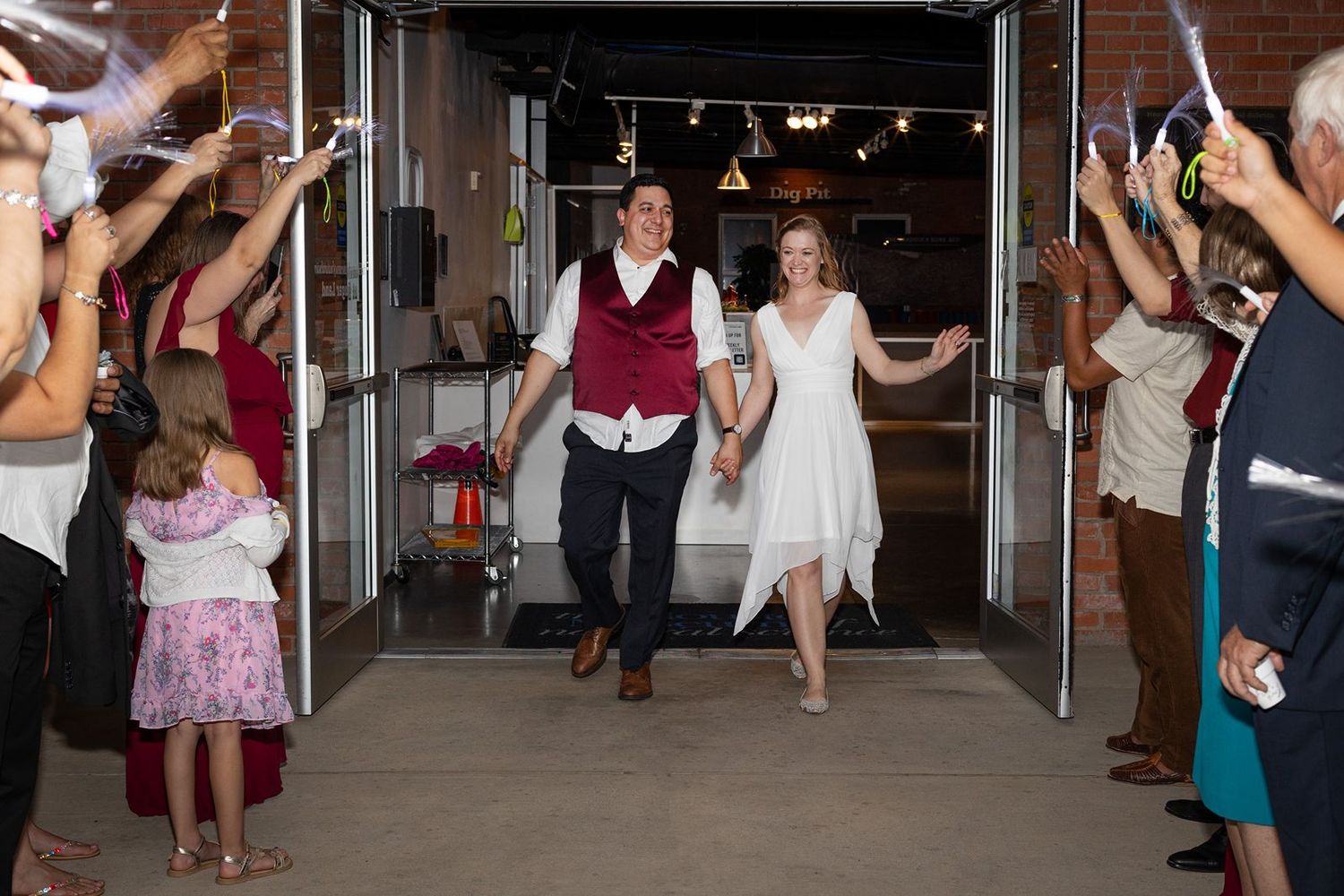 Wedding guests form a dance line on a wooden floor during a reception celebration.