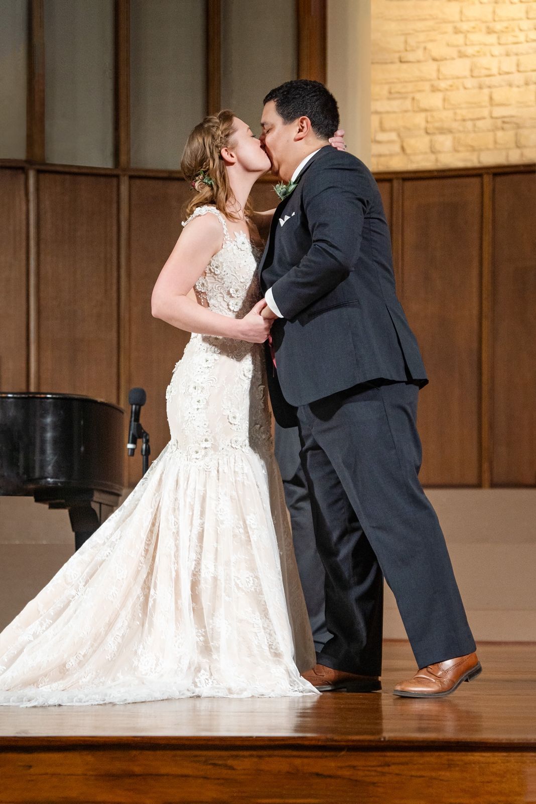 Bride and groom share first kiss in elegant church wedding ceremony.