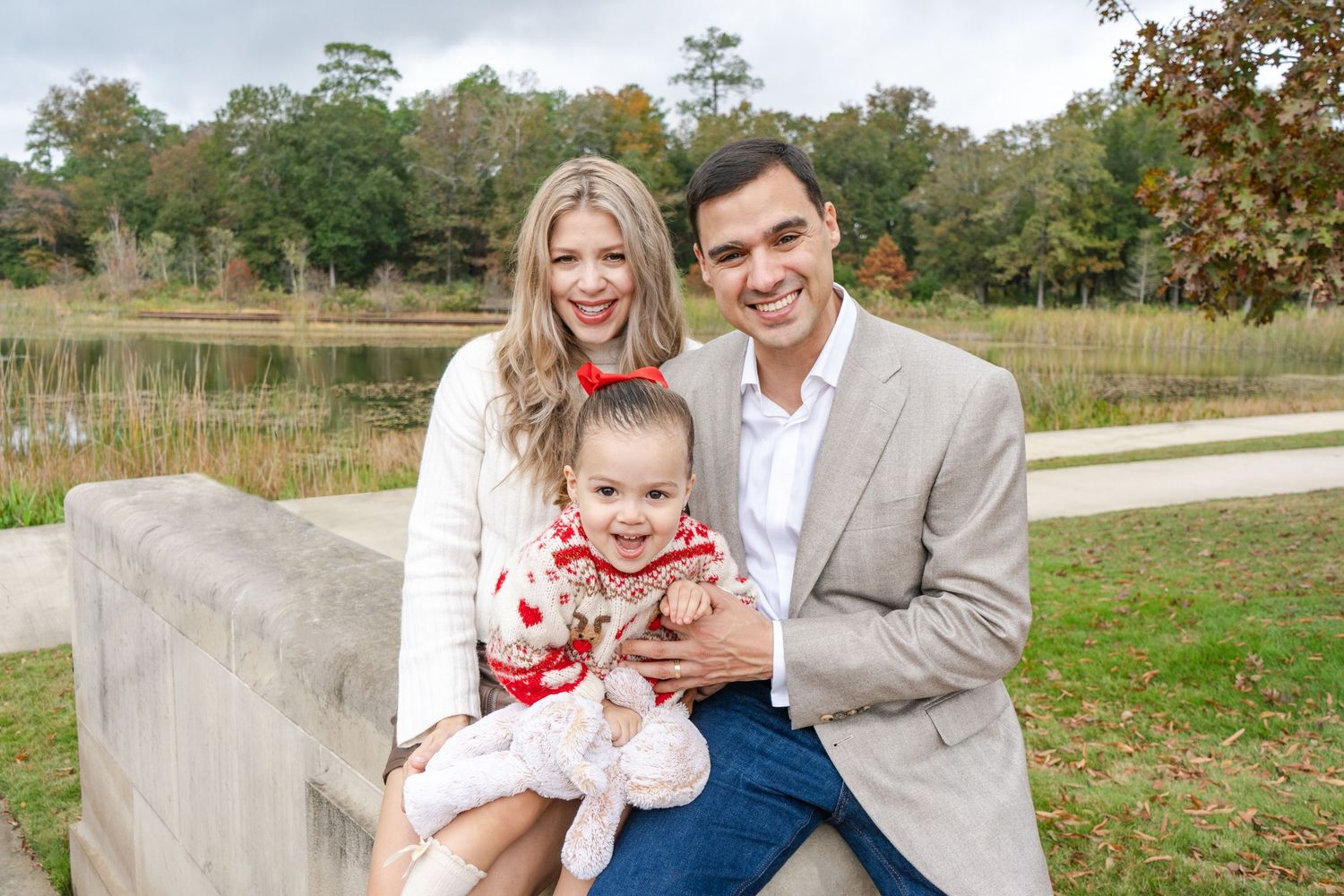 A family poses together outdoors in coordinating white and beige outfits during an autumn photo session.