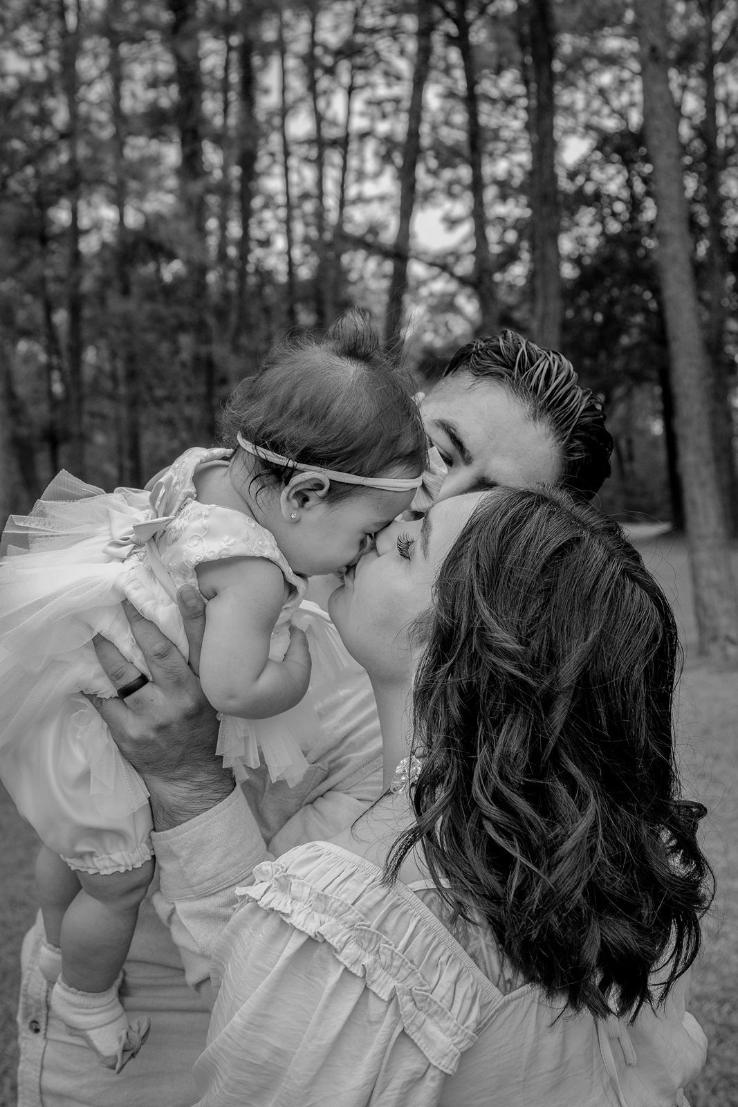 A series of four black and white photos showing a tender romantic moment between two people in a forest setting.