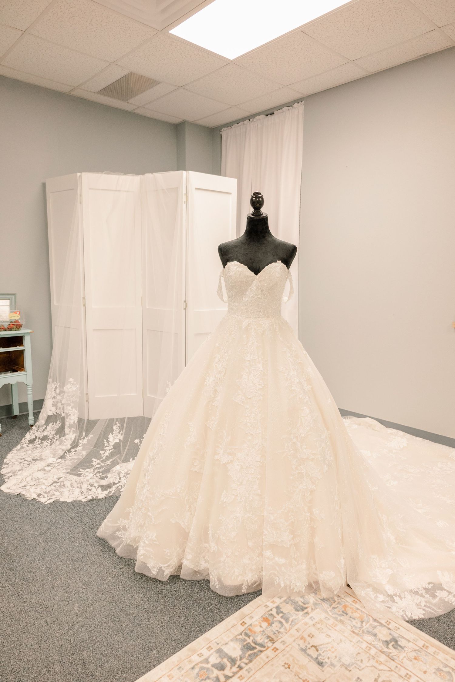 Elegant white wedding dresses with intricate lace details displayed on mannequins in a bridal boutique.