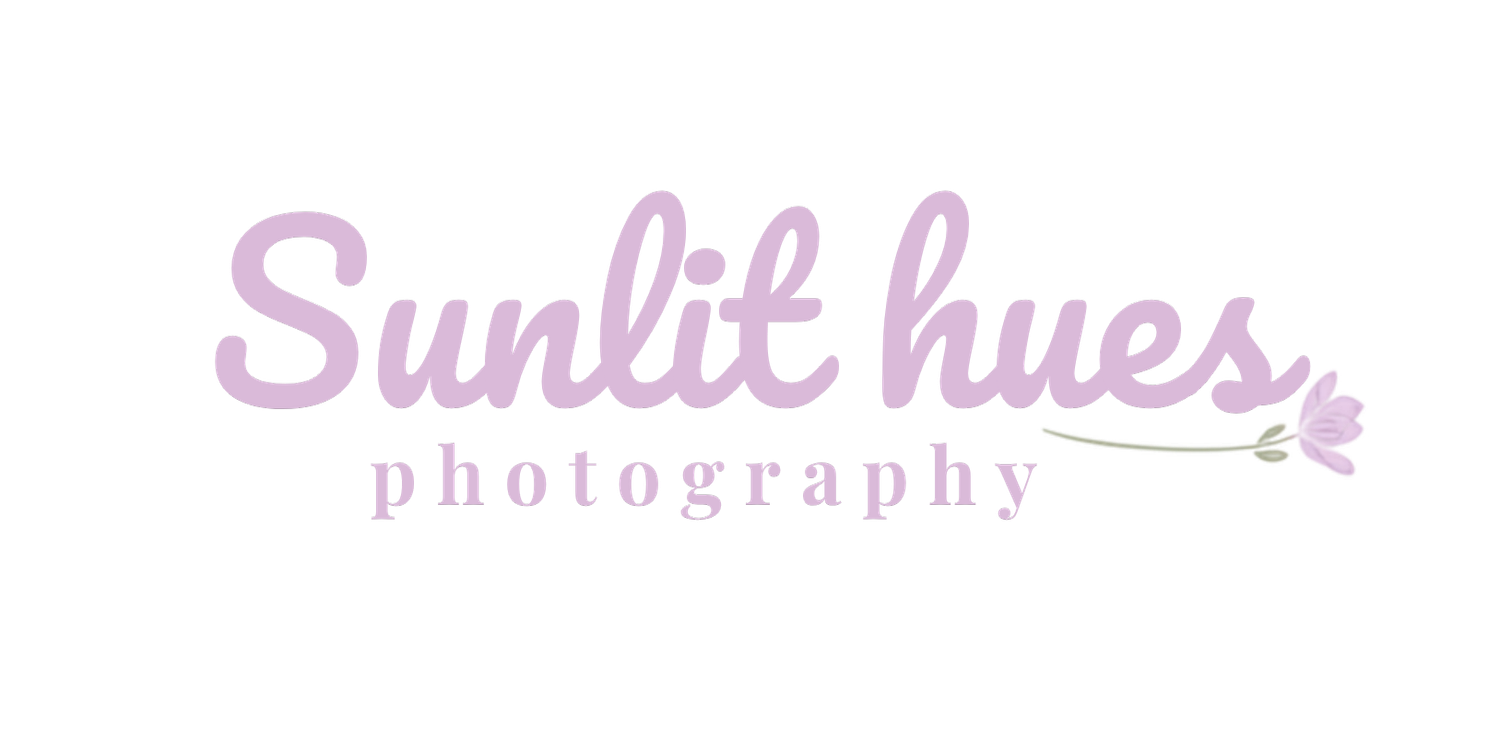 Sunlit Hues Photography logo featuring elegant script font in soft purple tones with a delicate floral accent.