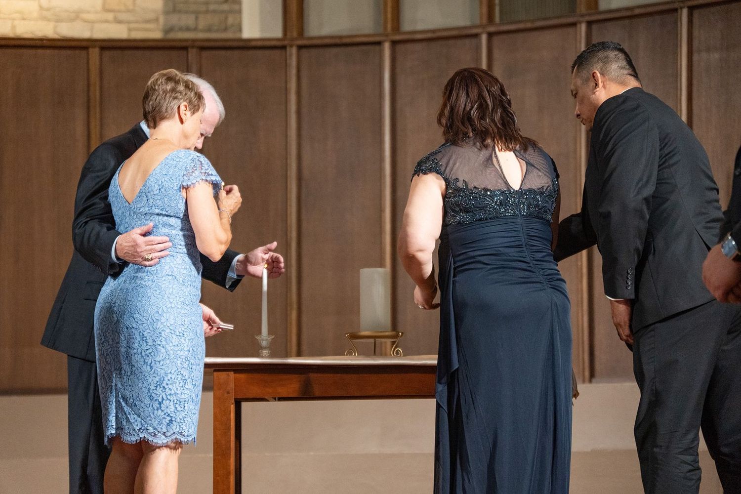 Two couples participate in a unity candle ceremony at an elegant church wedding altar.