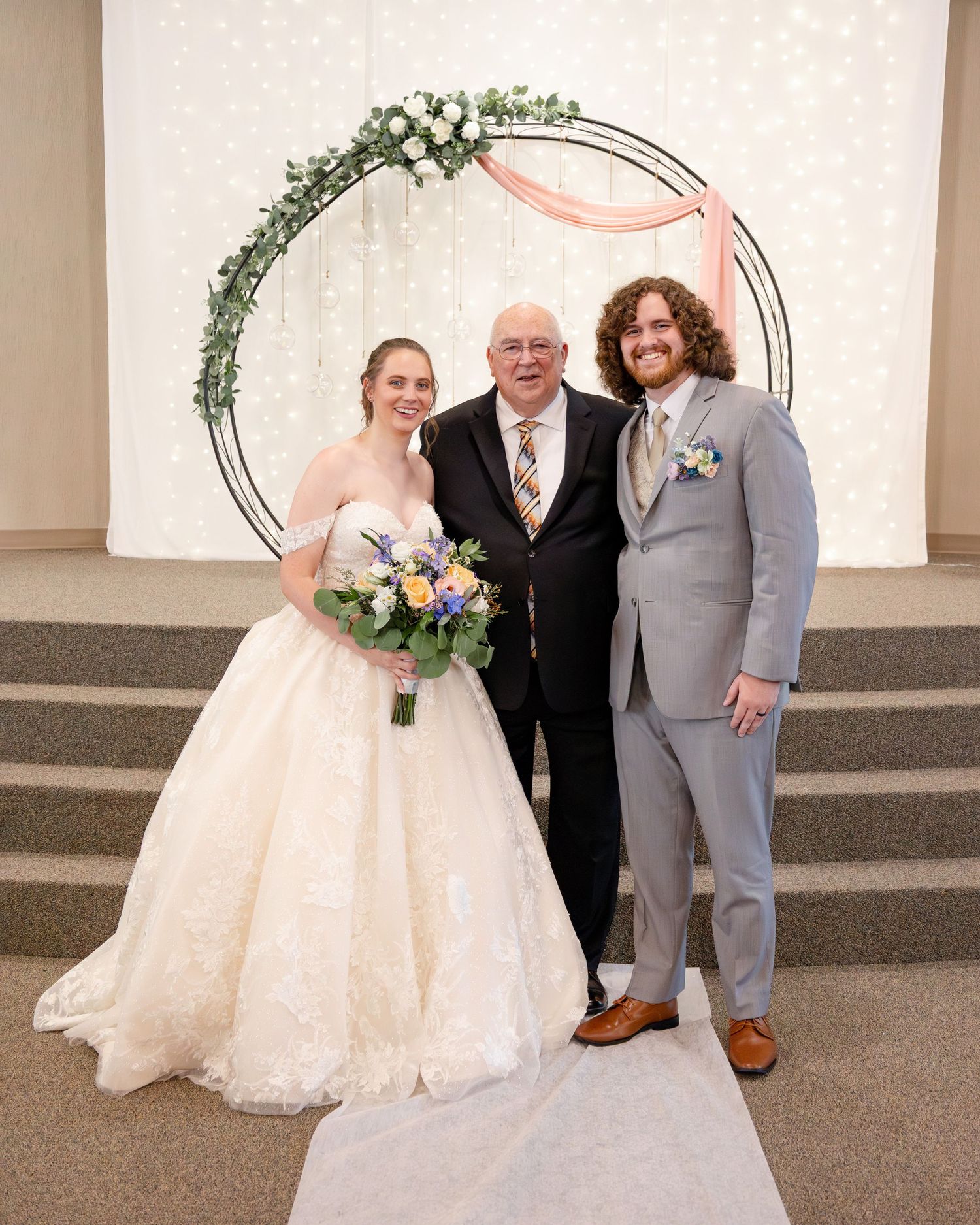 Wedding ceremony staged in a church with floral arch and tiered platform.
