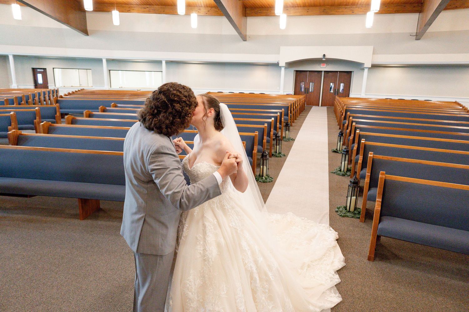 Wedding couple embraces during first look photos in a church sanctuary with natural light streaming in.