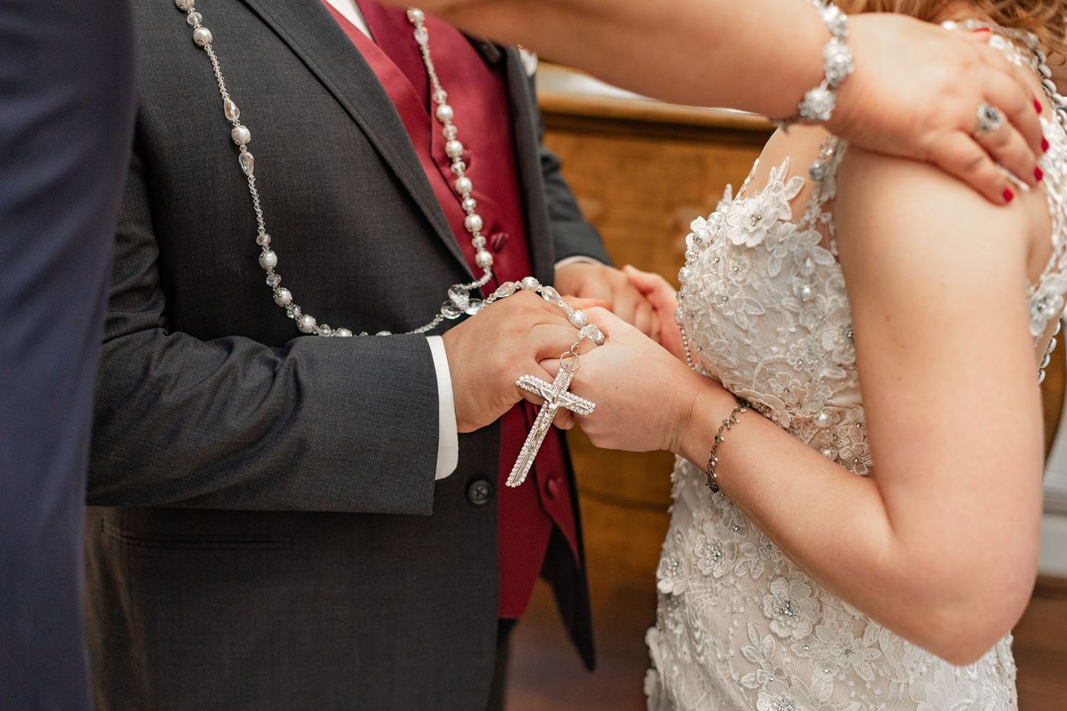 Close-up view of hands showing wedding rings during a formal ceremony with elegant attire.