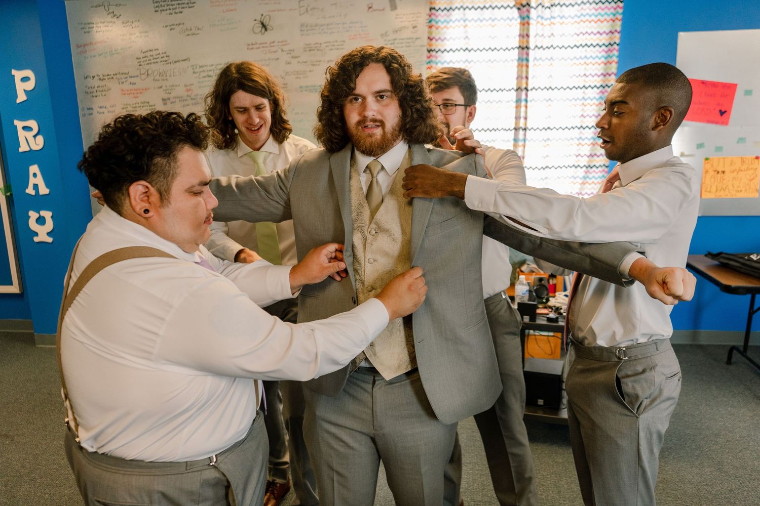People in white shirts and gray suits interacting energetically in a decorated room.