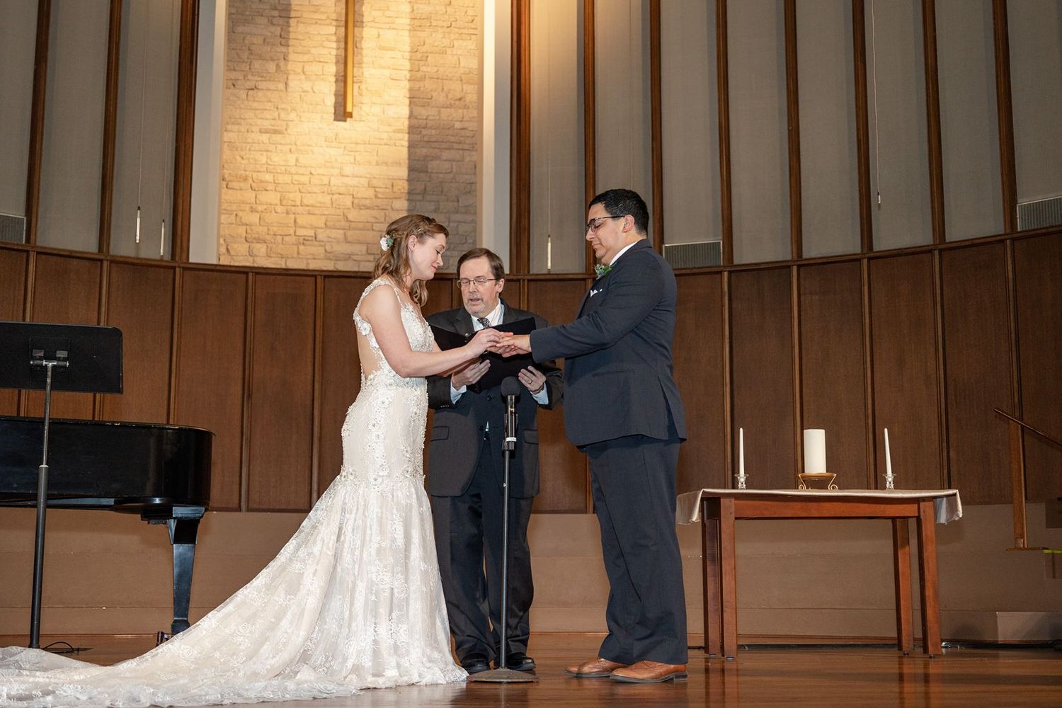 Wedding ceremony taking place in a church sanctuary with wooden paneled walls and warm lighting.