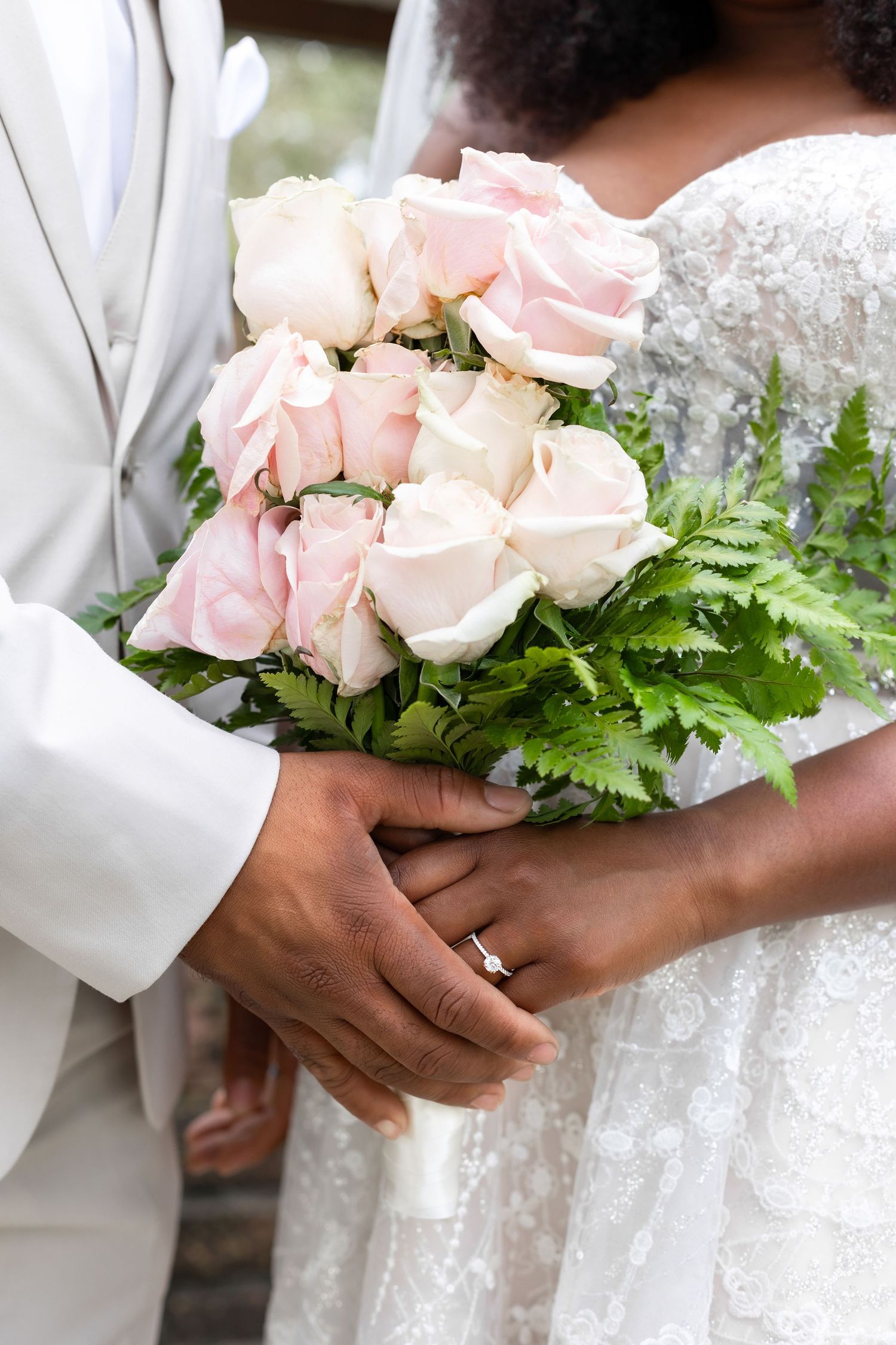 Delicate pink roses and white floral bouquet held with lace wedding dress.