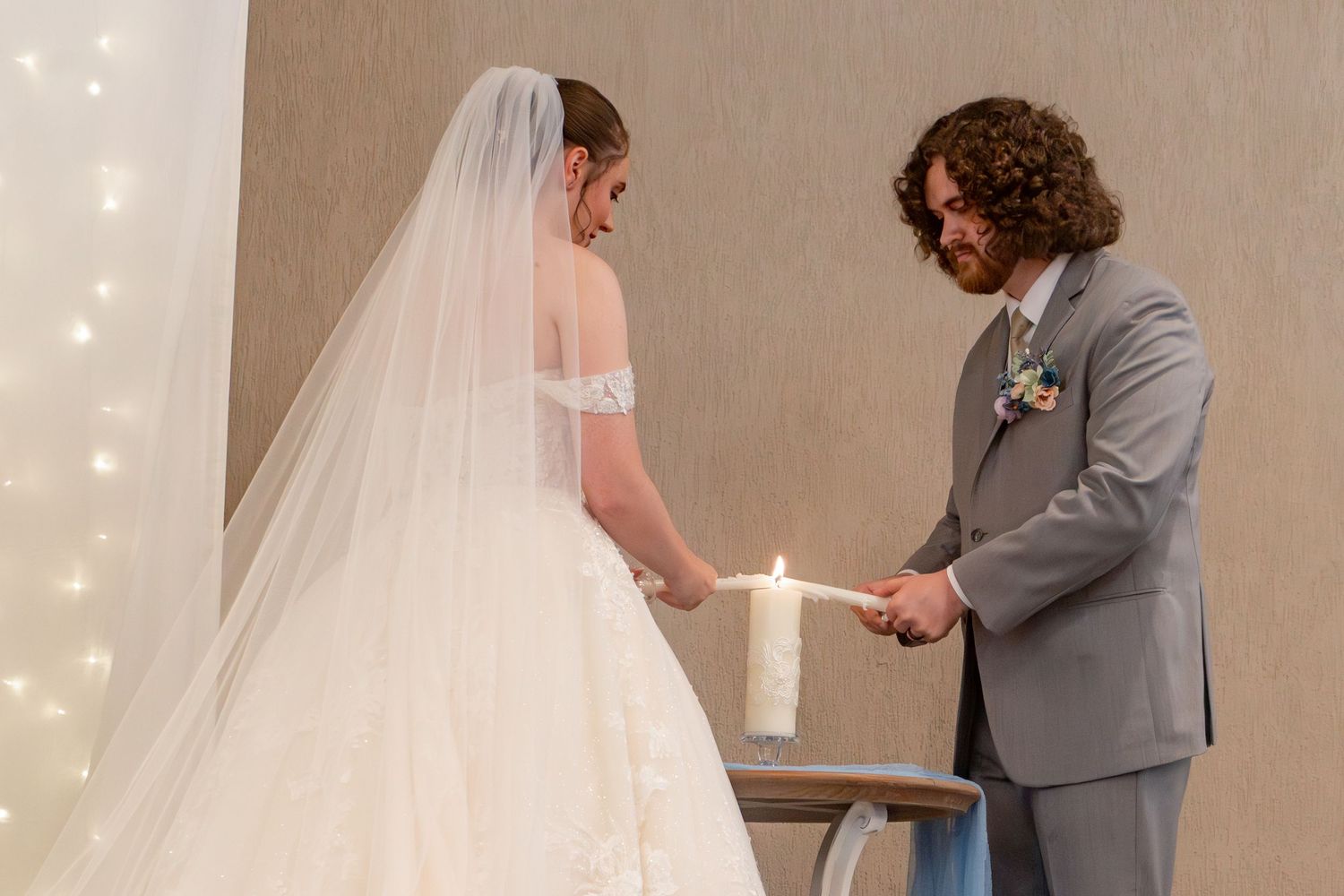 A tender moment captured between two people during a wedding ceremony with twinkle lights in the background.