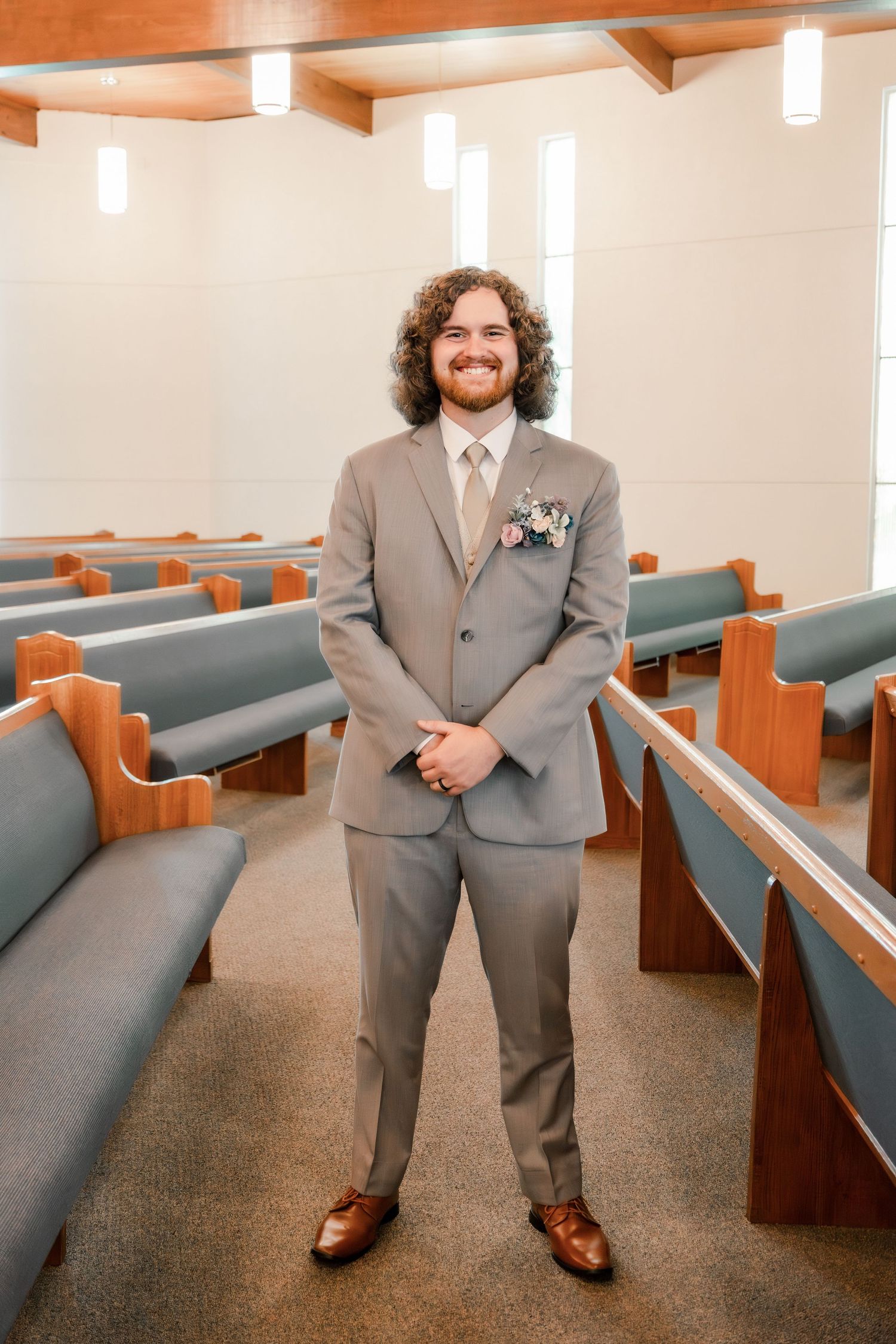 A wedding day portrait in a church setting featuring a grey suit and floral boutonniere.