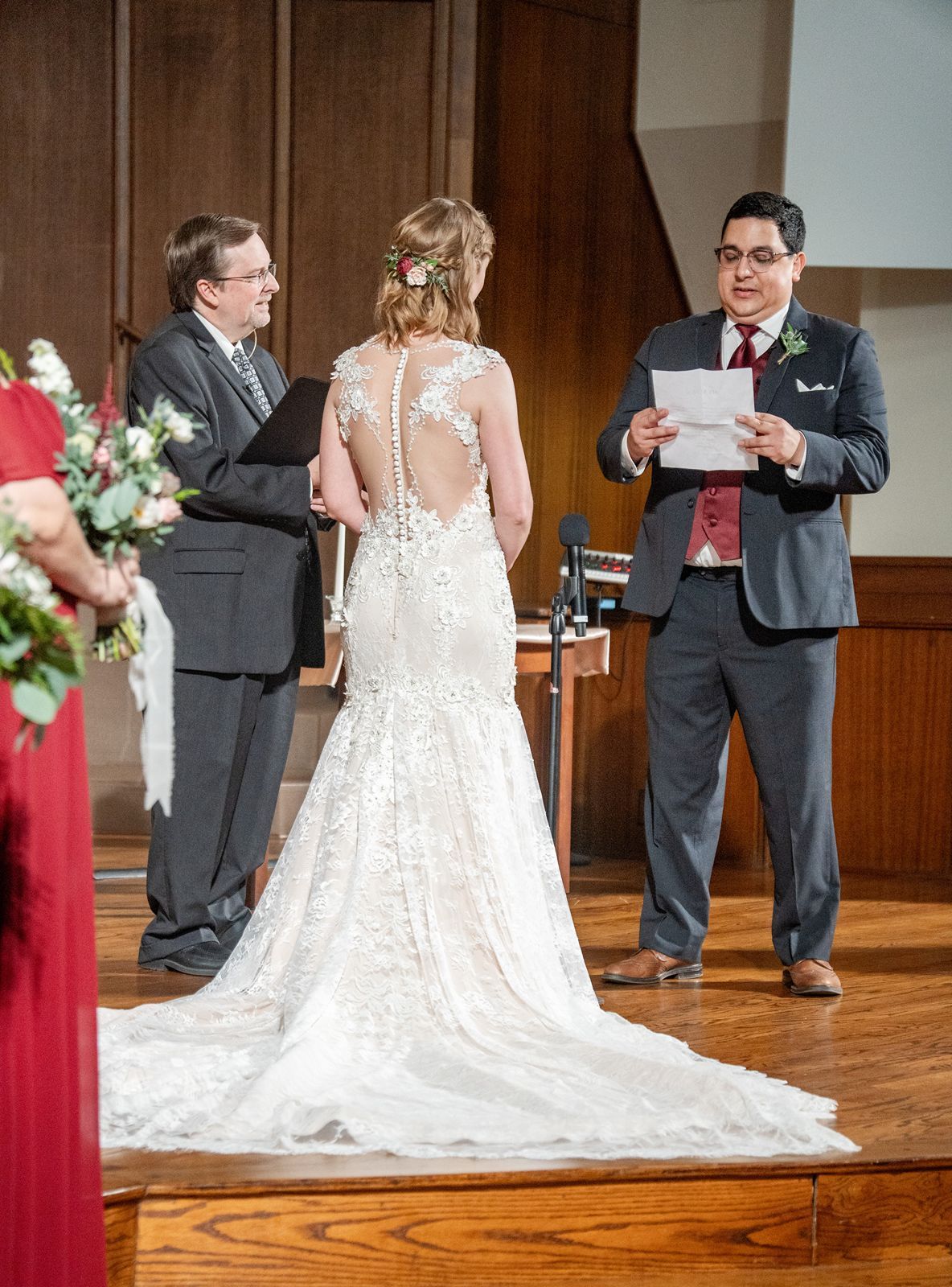 Groom reads vows to his bride in a lace mermaid gown during a church wedding ceremony.