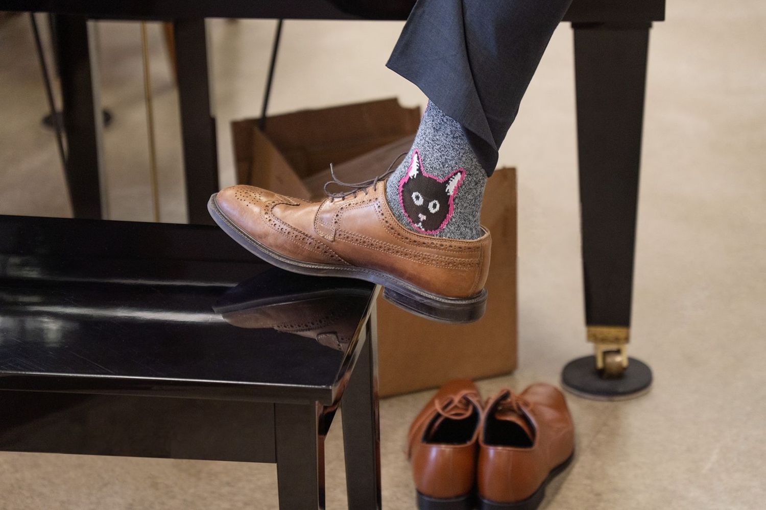 Groom wearing fun black cat novelty socks with brown wingtip dress shoes at wedding.