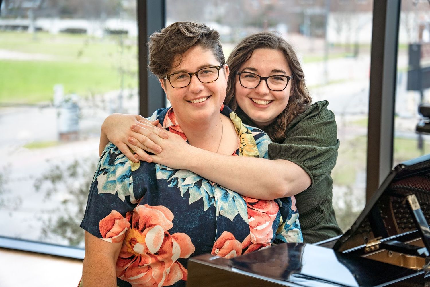 Two people share a joyful moment while sitting at a table in a bright indoor space.