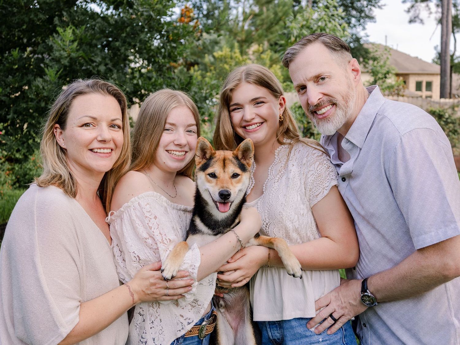 Family and their Shiba Inu dog share joyful moments together during an outdoor photo session.