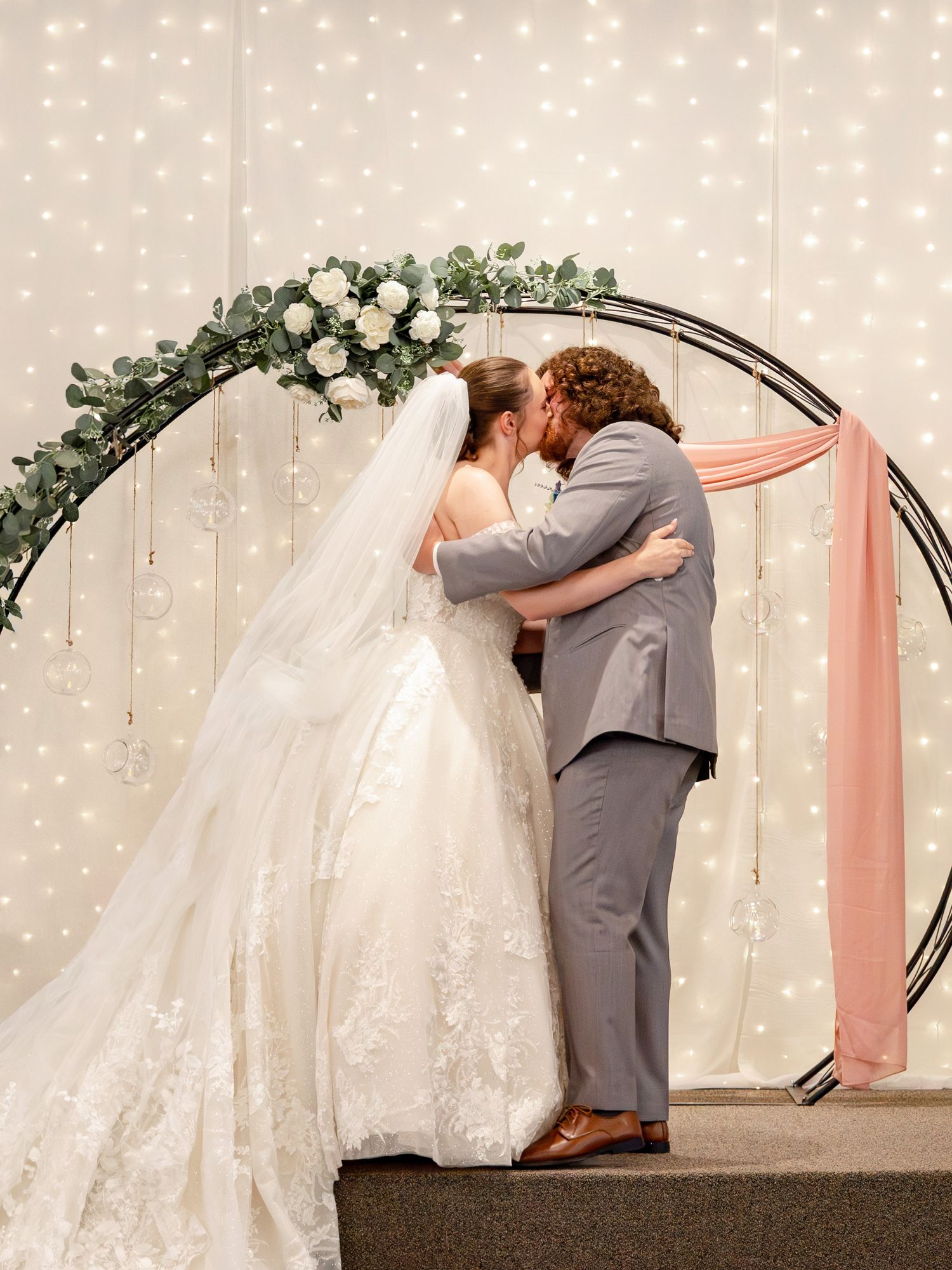 A romantic wedding ceremony moment beneath string lights and floral decorations.
