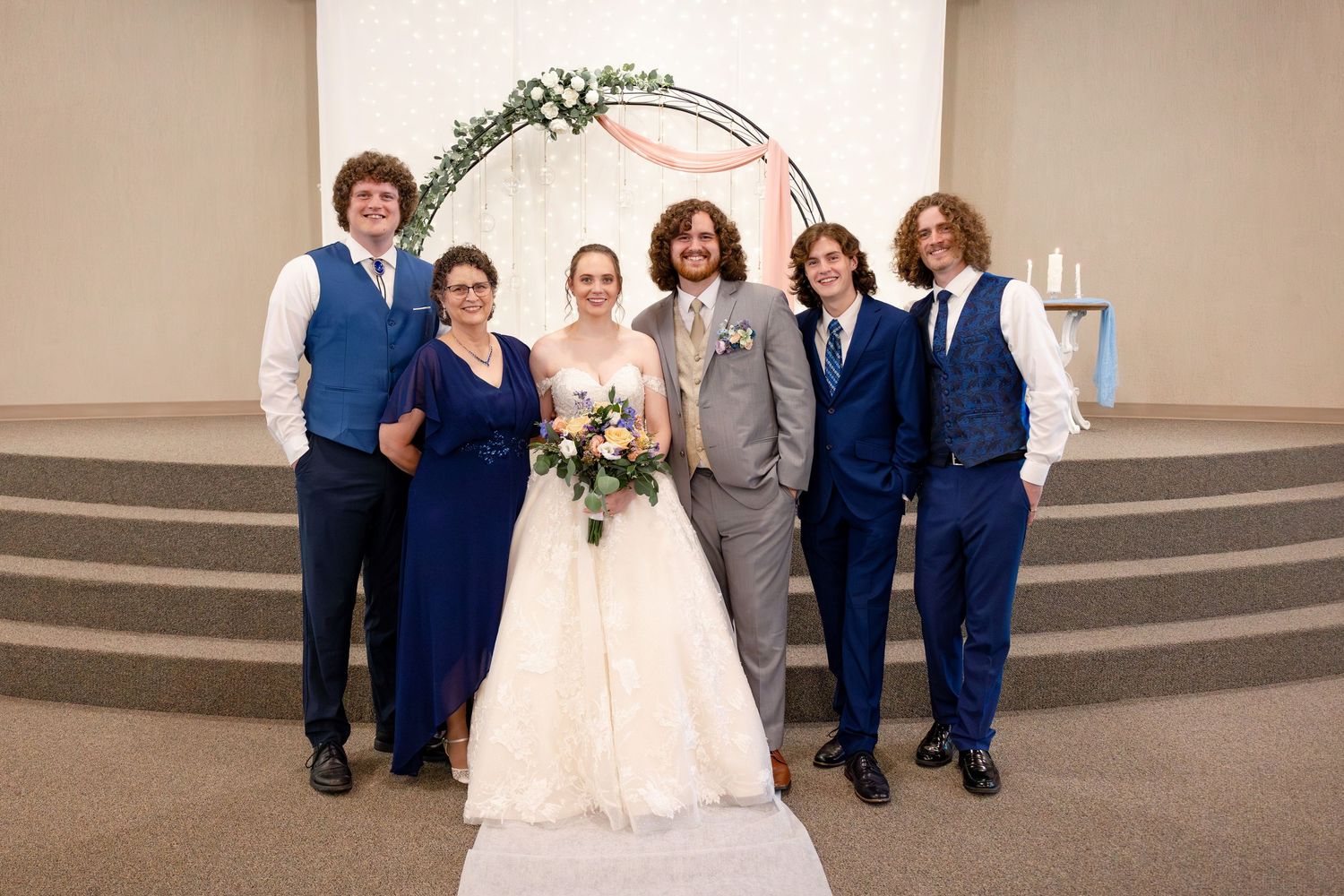 Large group photo of wedding party and family members inside church sanctuary.