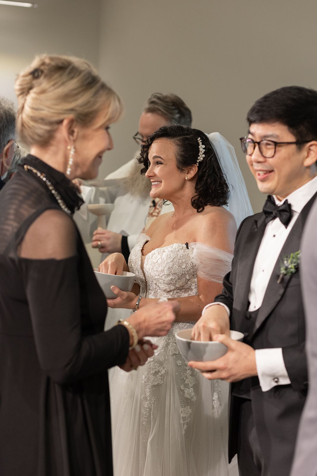 Wedding party members share a joyful moment during a receiving line at an elegant indoor celebration.