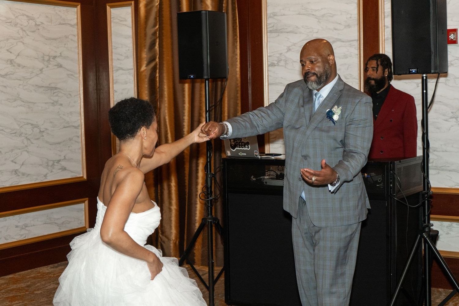 Bride and groom share a romantic first dance at elegant wedding reception with DJ in background.