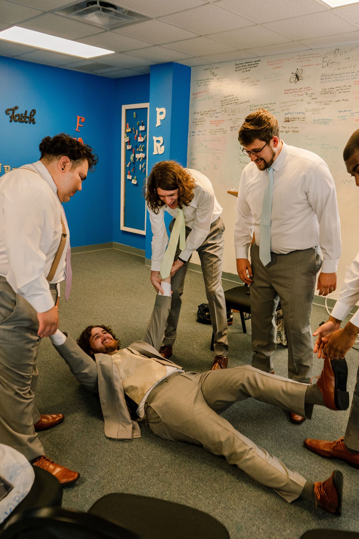 People acting out dramatic poses on the carpeted floor of a meeting room.