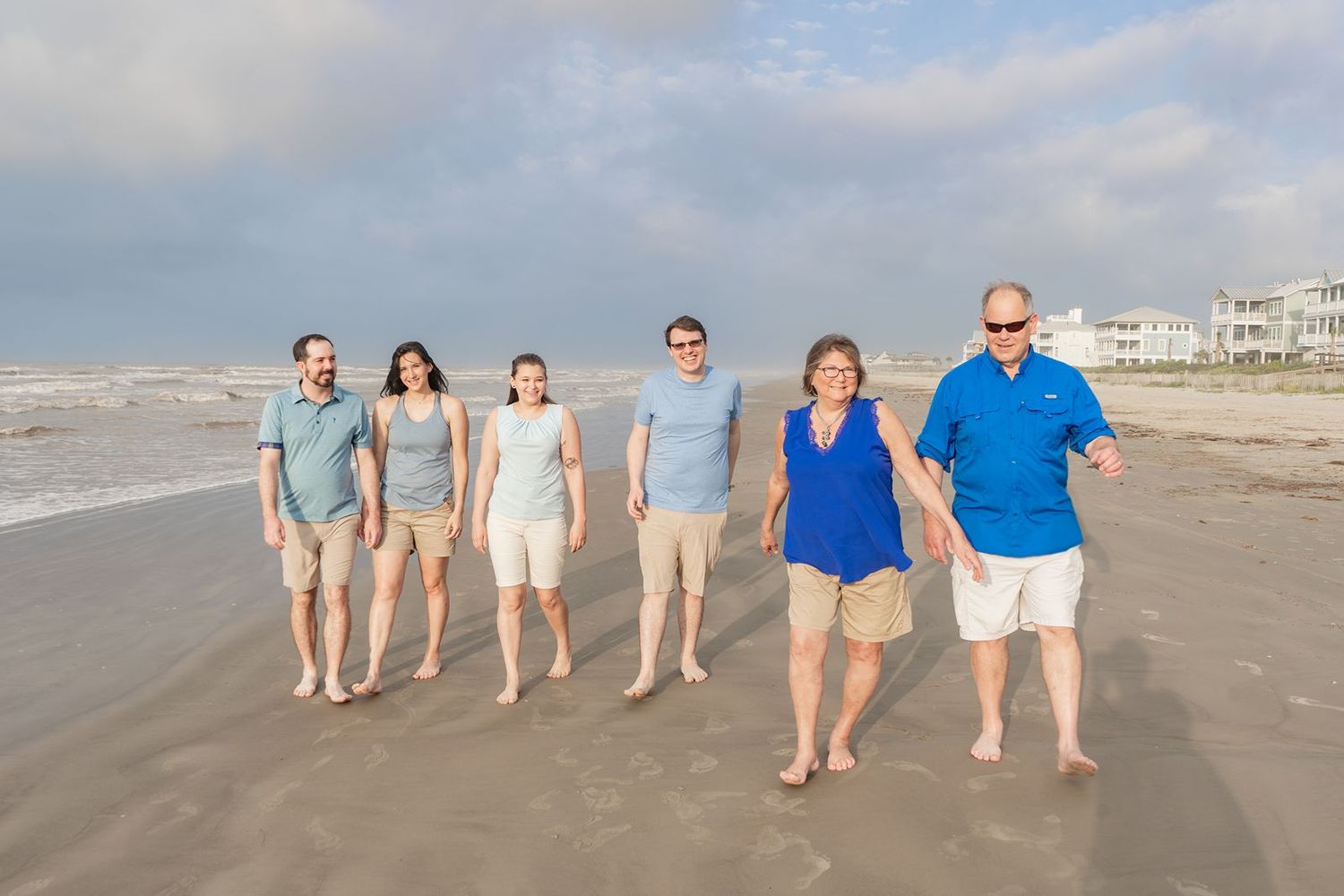 Group of people walking together on a sandy beach during a sunny day.
