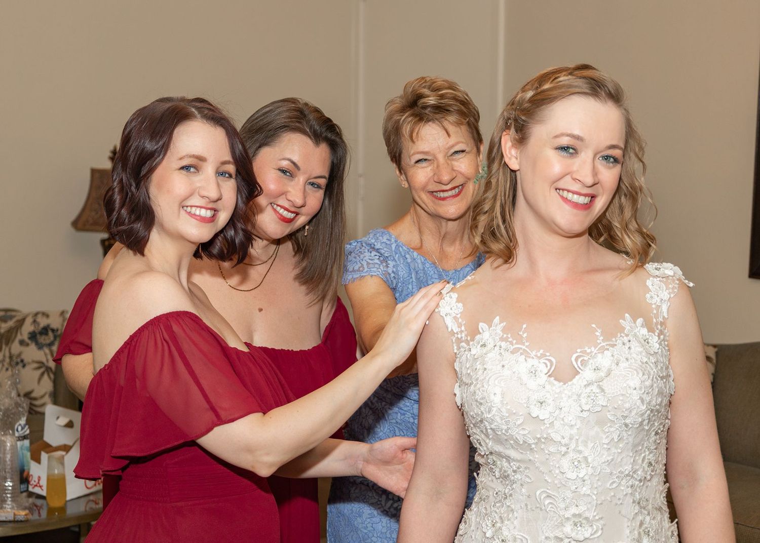 A bride in an elegant white lace gown shares a joyful moment with her wedding party.