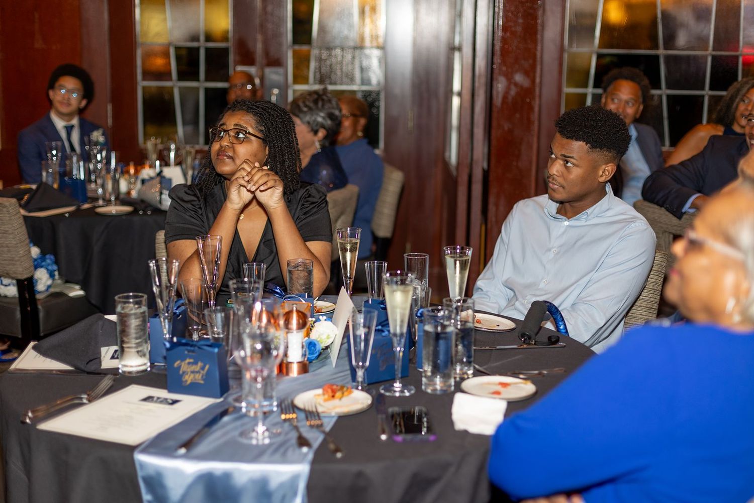 Guests seated at decorated tables during an evening wedding reception event.