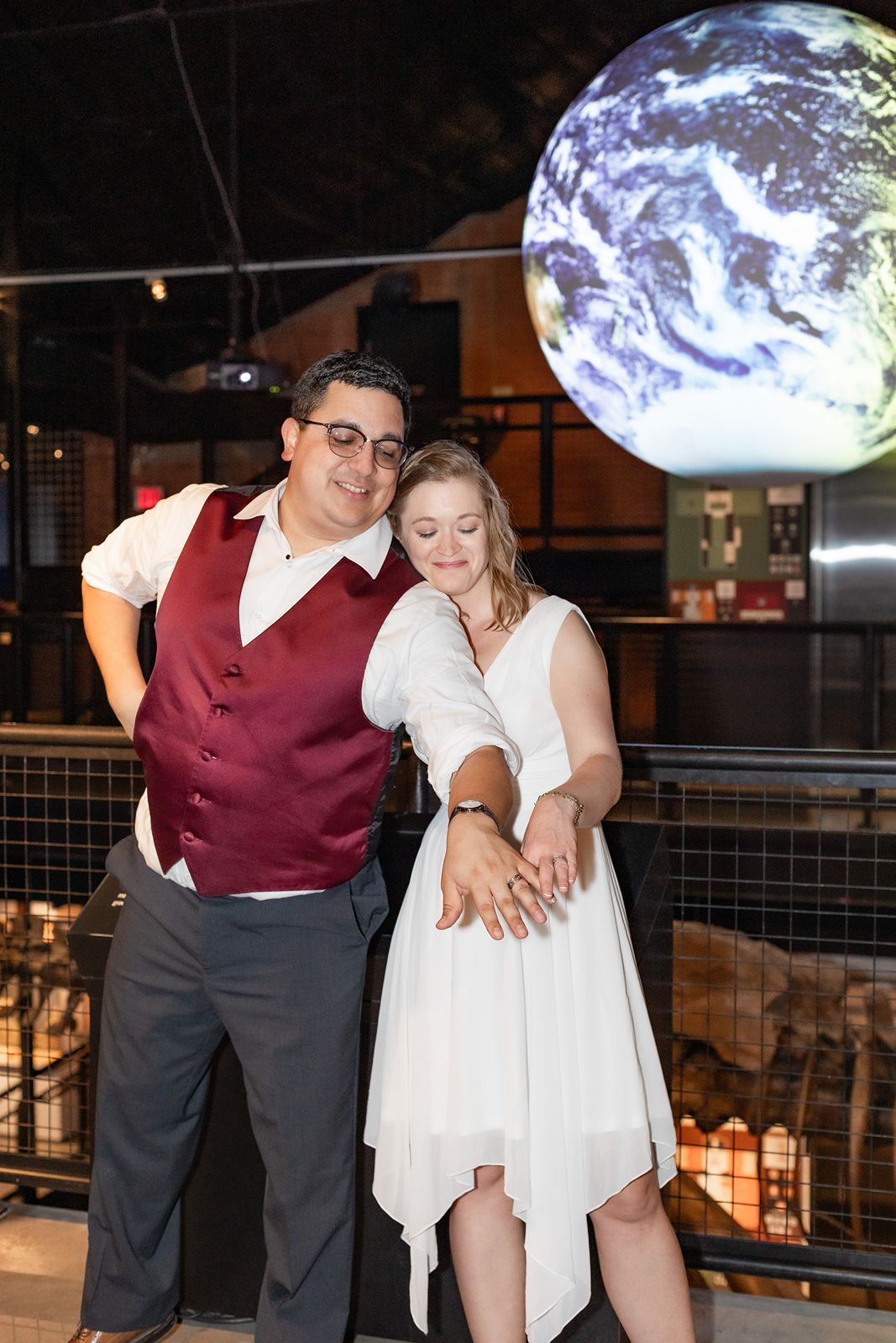 Couple poses in front of Earth globe display at museum engagement photo shoot.