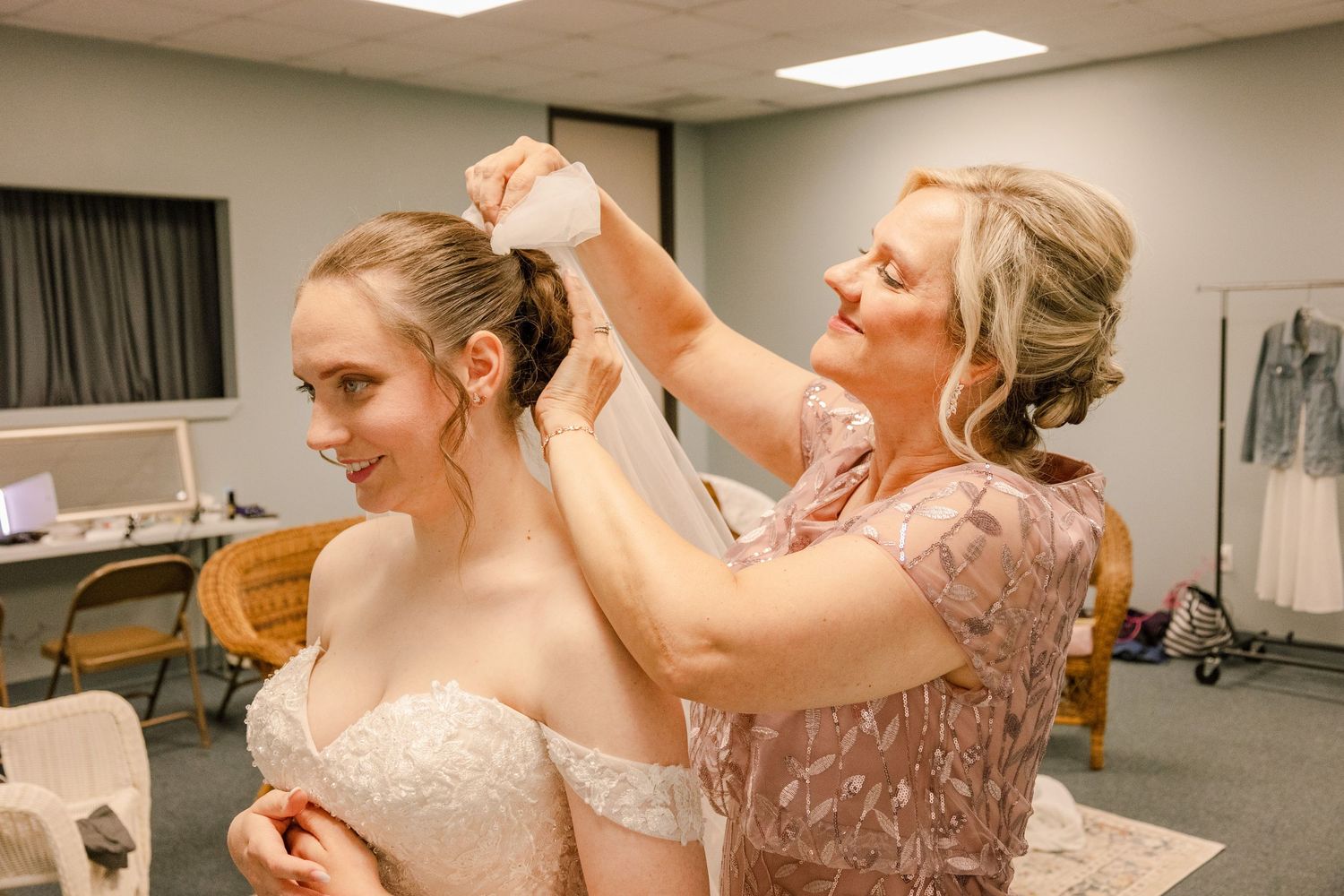 Wedding dress fitting with rose gold sequined bridesmaid helping adjust the gown.
