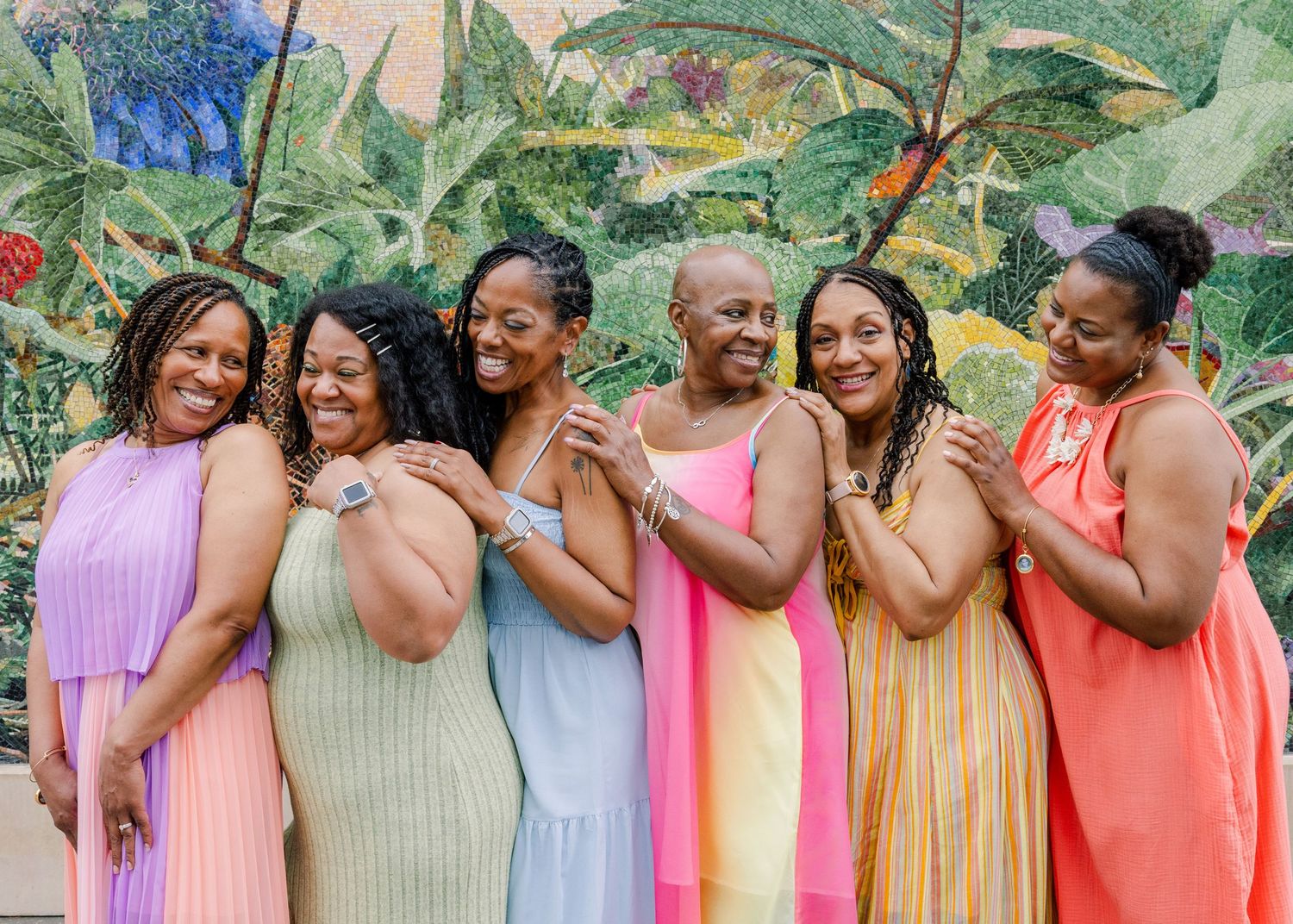 Group photo of friends in pastel dresses standing together outdoors.